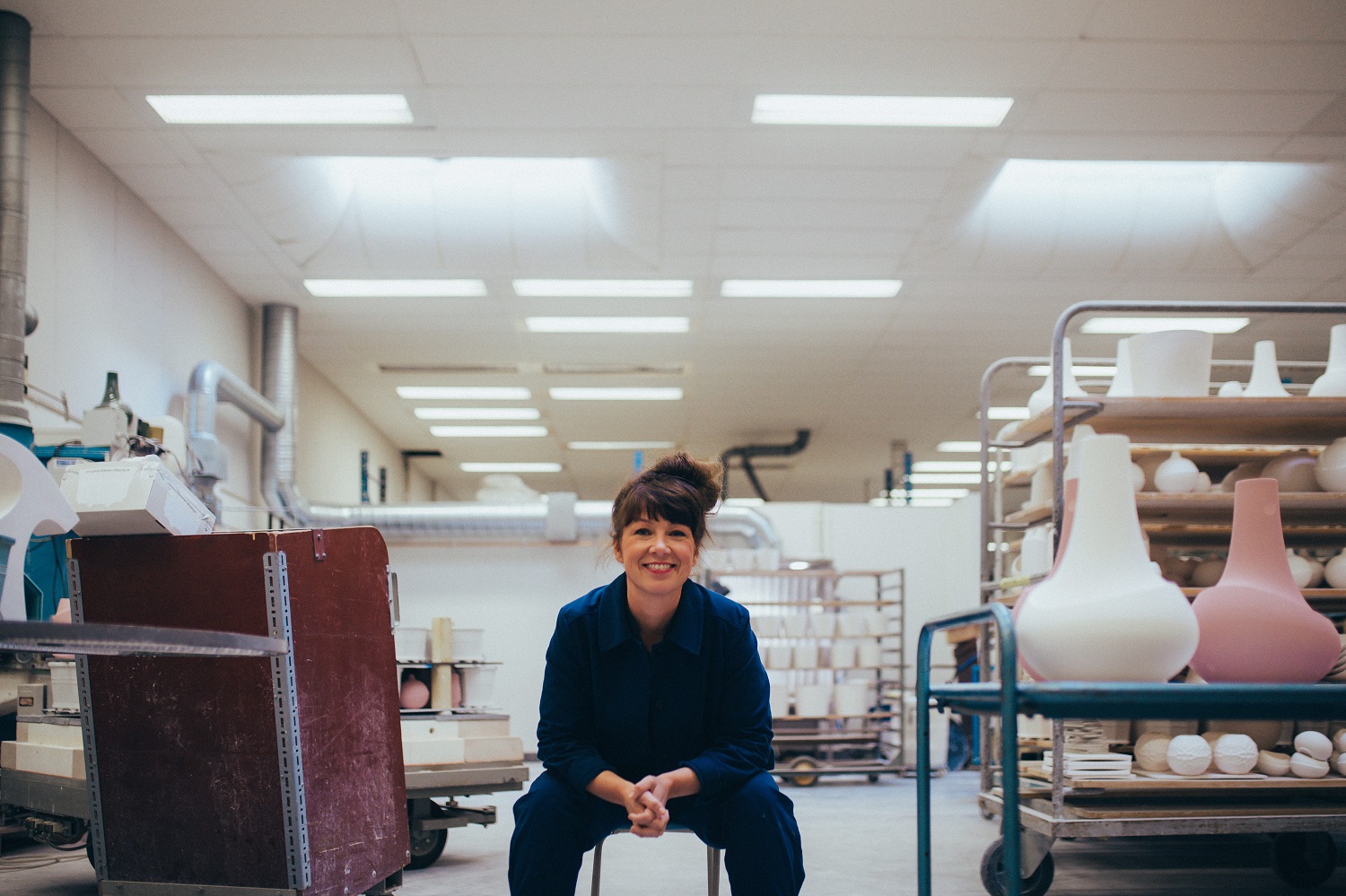 A woman is sitting on a chair in a ceramic workshop