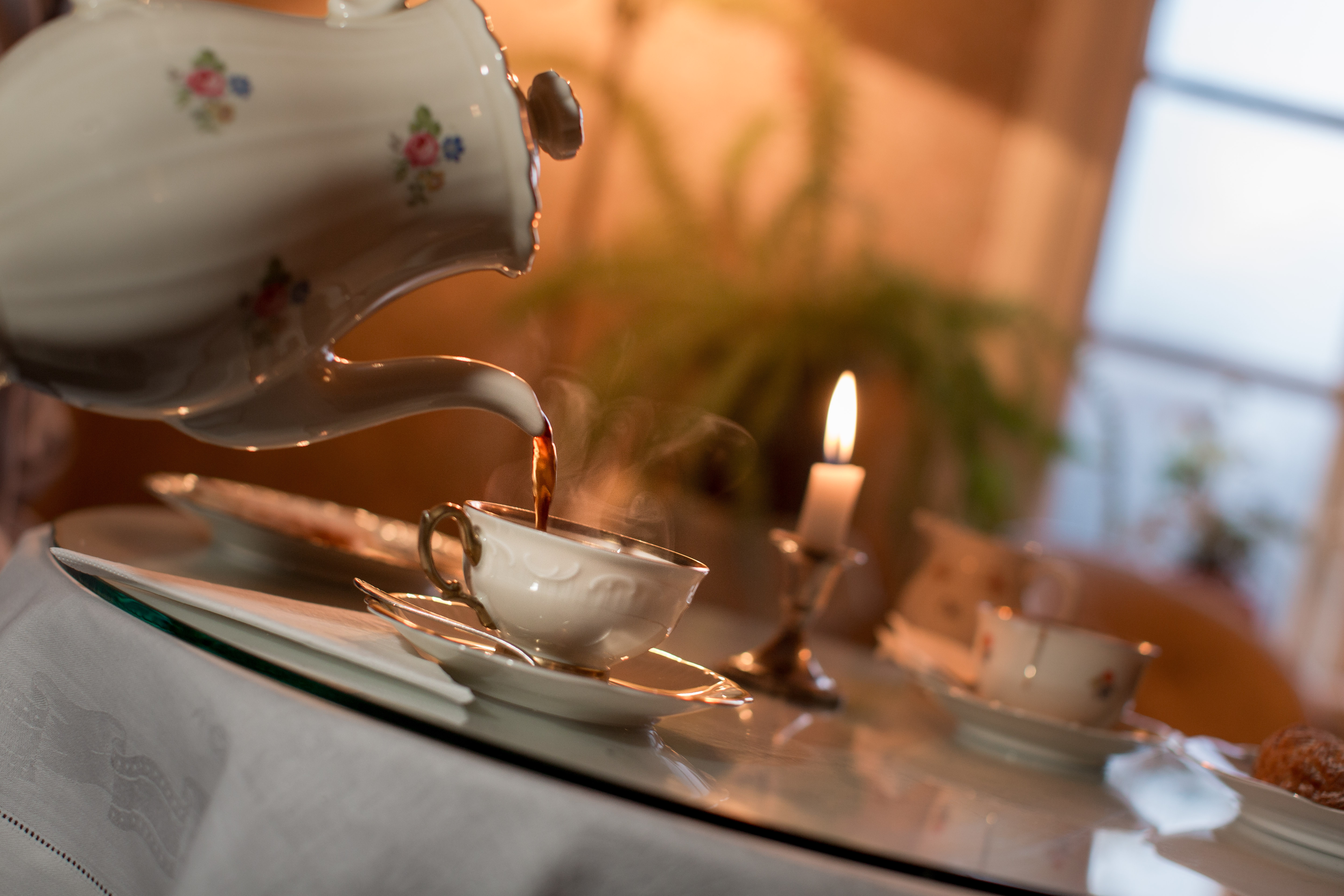 Någon häller upp rykande kaffe från en gammal kaffekanna i porslin.