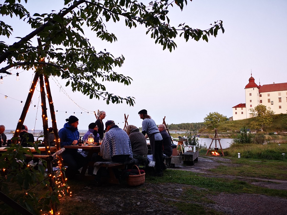 Bord som står i naturen med läckö slott i bakgrunden.
