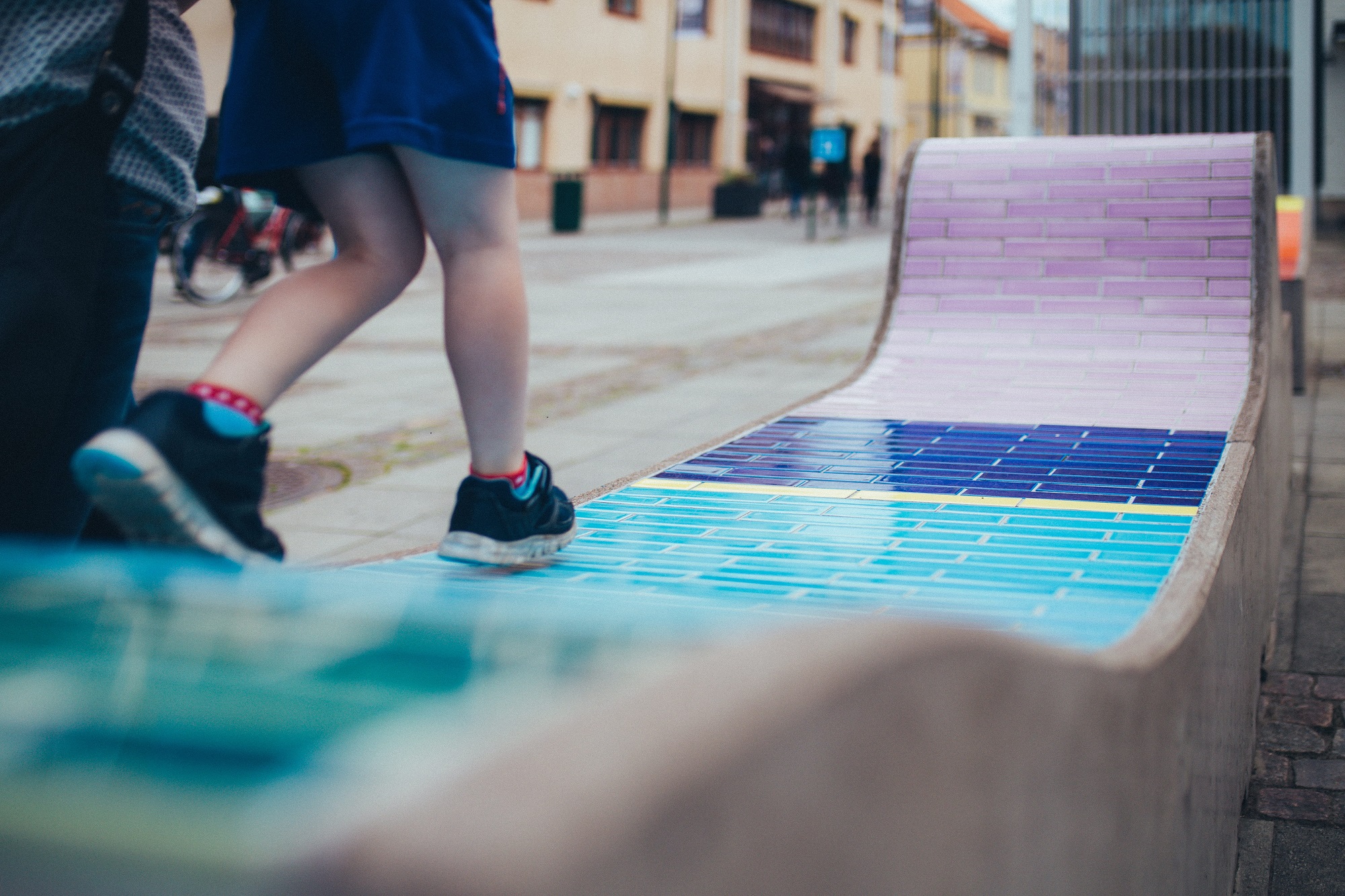 En soffa i betong med kakelplattor i olika färger på.