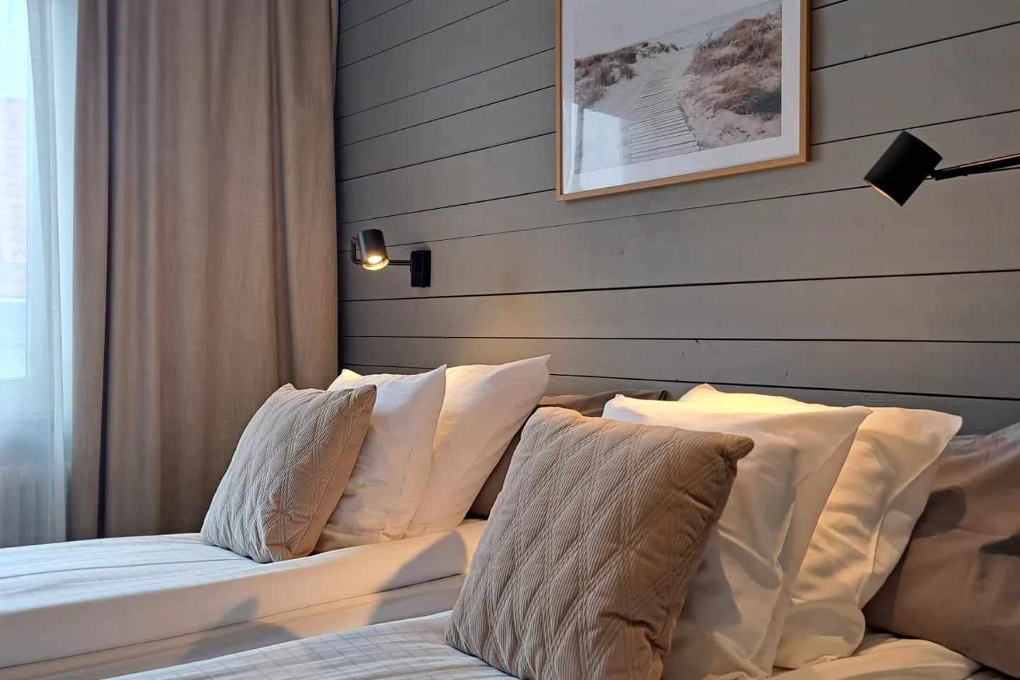 Hotelroom with two beds against a wall of grey wooden panel.