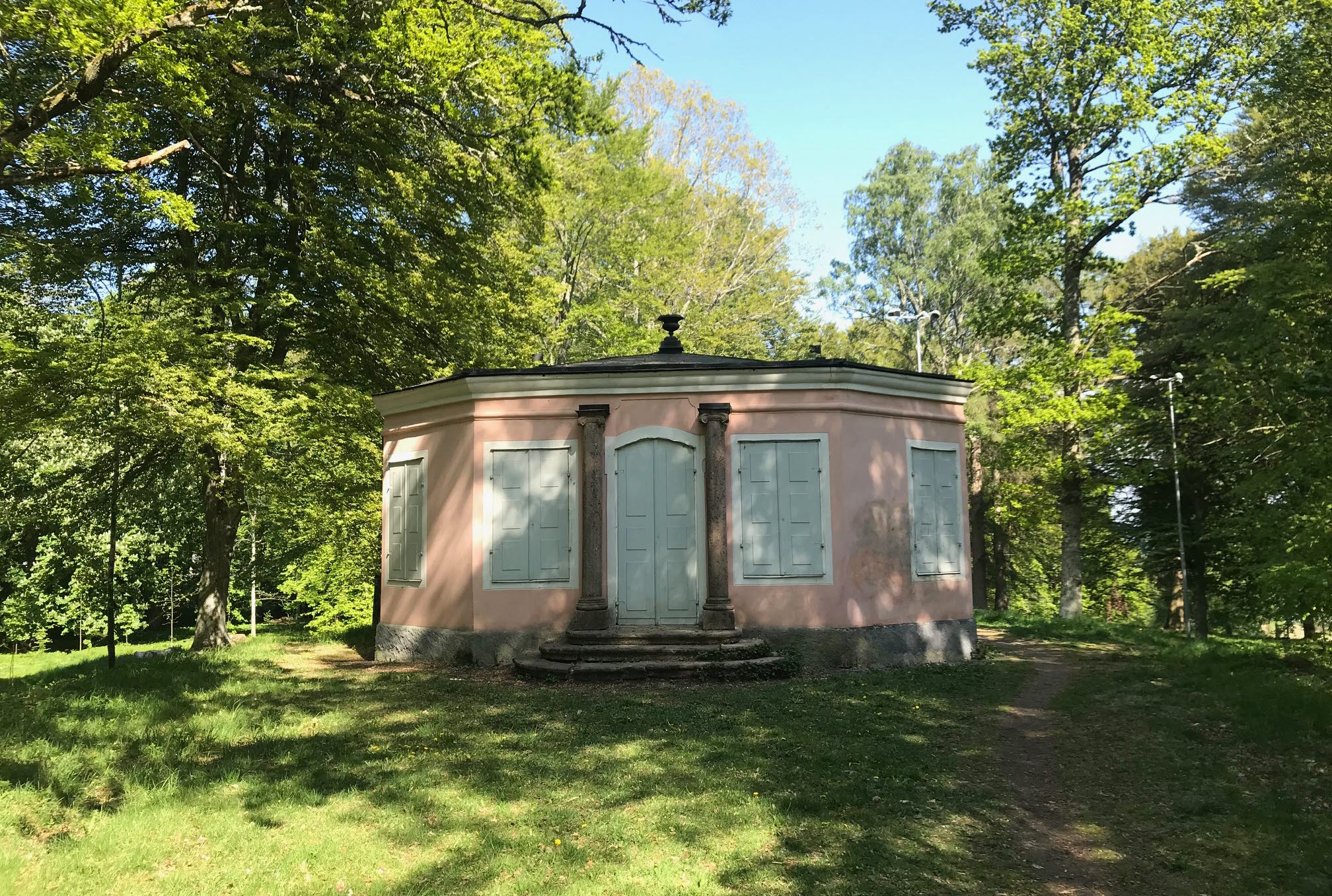 Rosa lusthus mitt i den gröna skogen. 