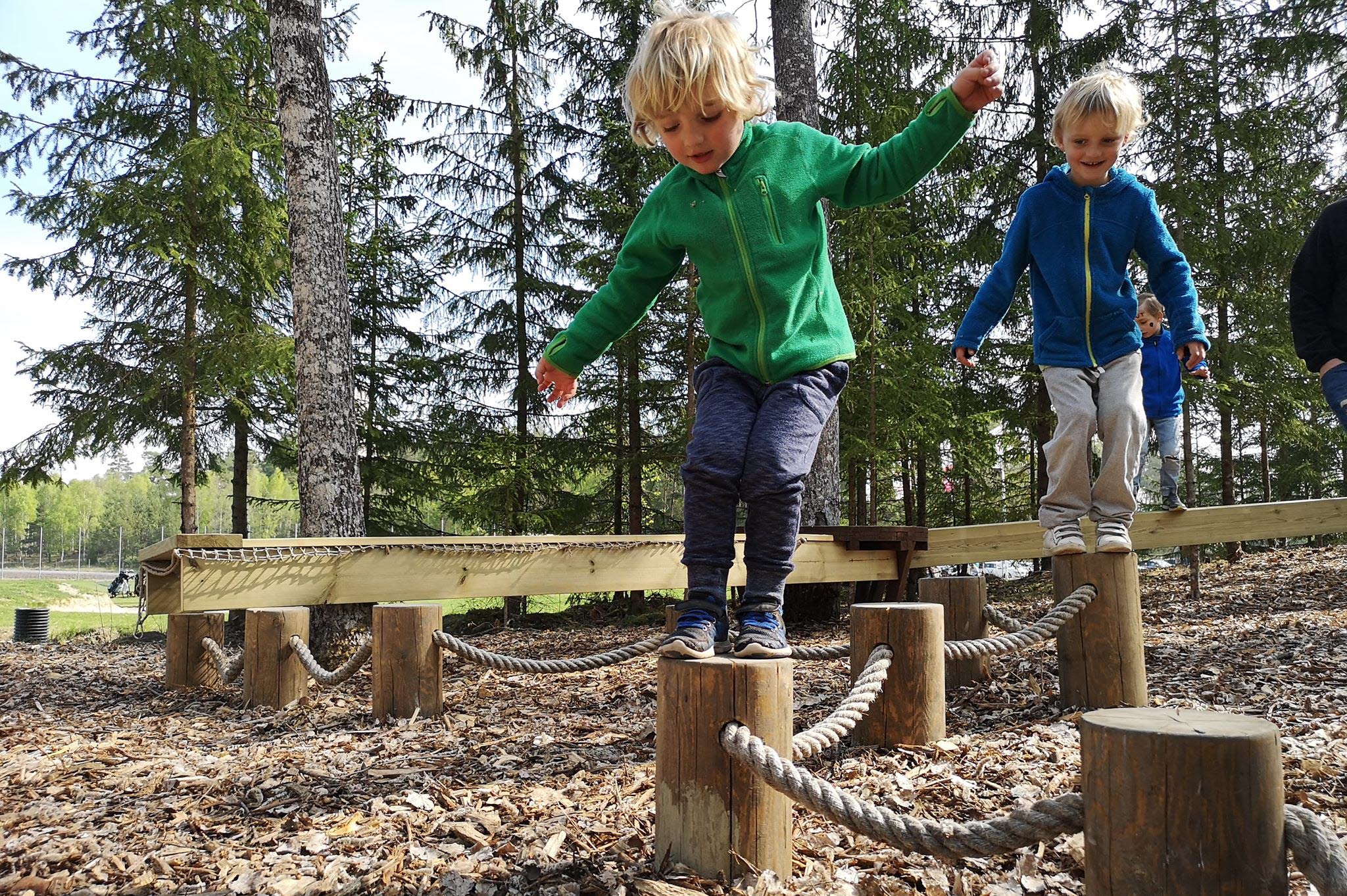 Två barn som leker på en hinderbana i naturen