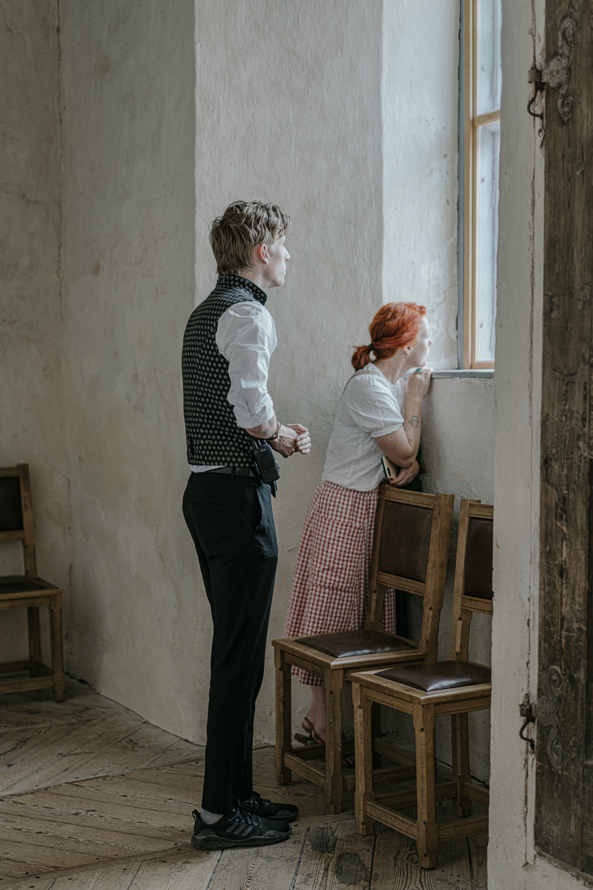 Kvinna tittar ut genom fönster på Läckö Slott med en manlig slottsguide bakom sig