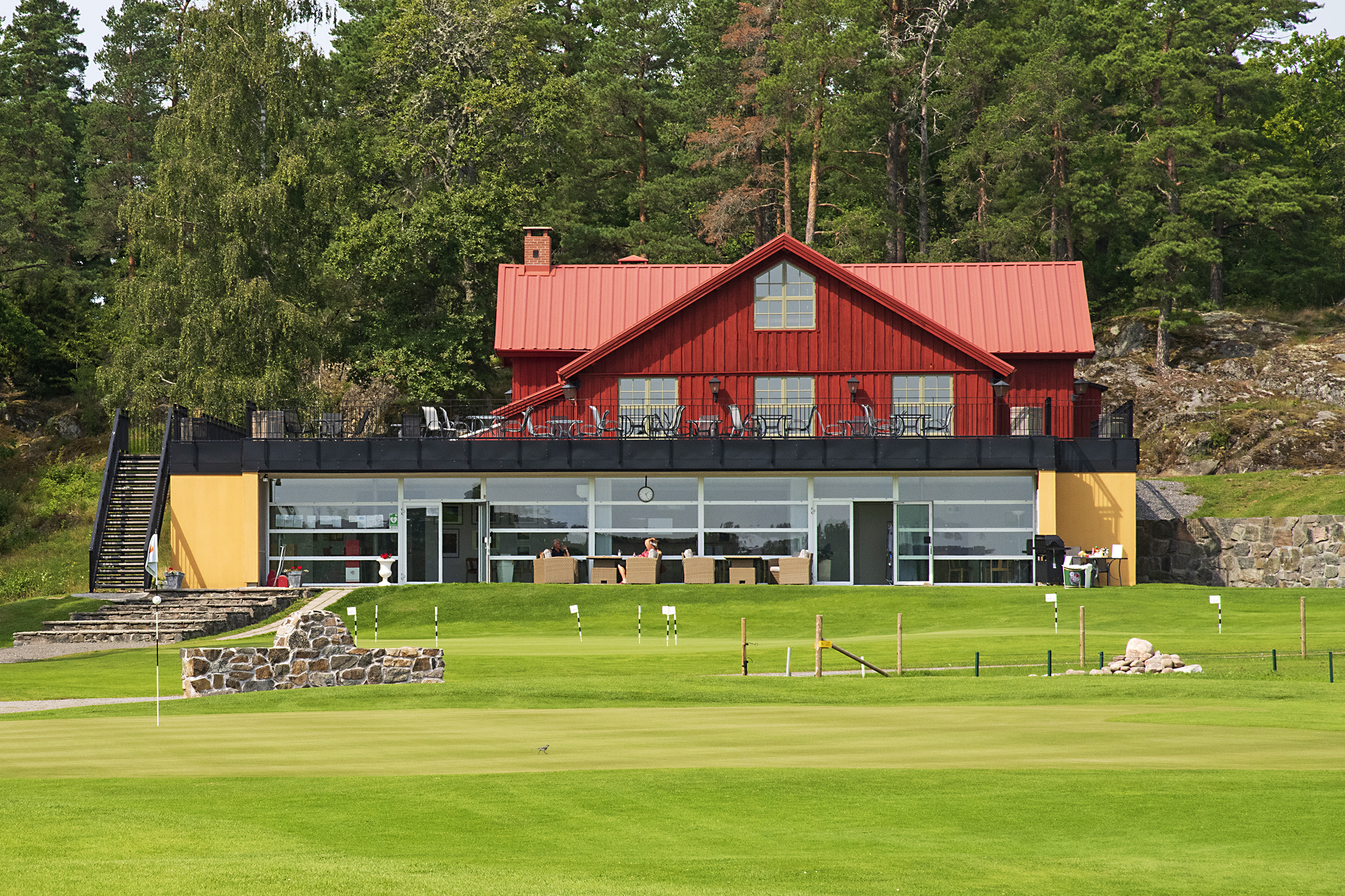 A red house with a green golf course in front
