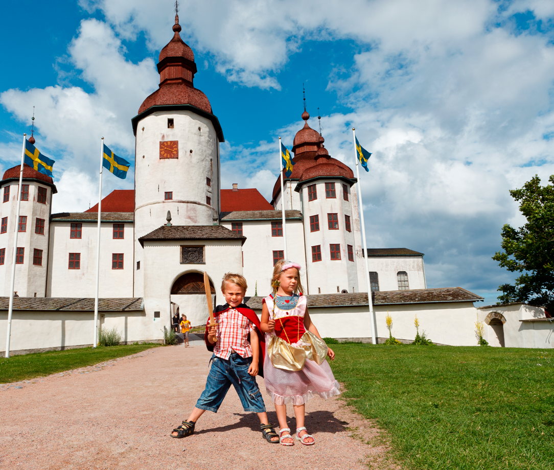 Två barn framför ett vitt slott.