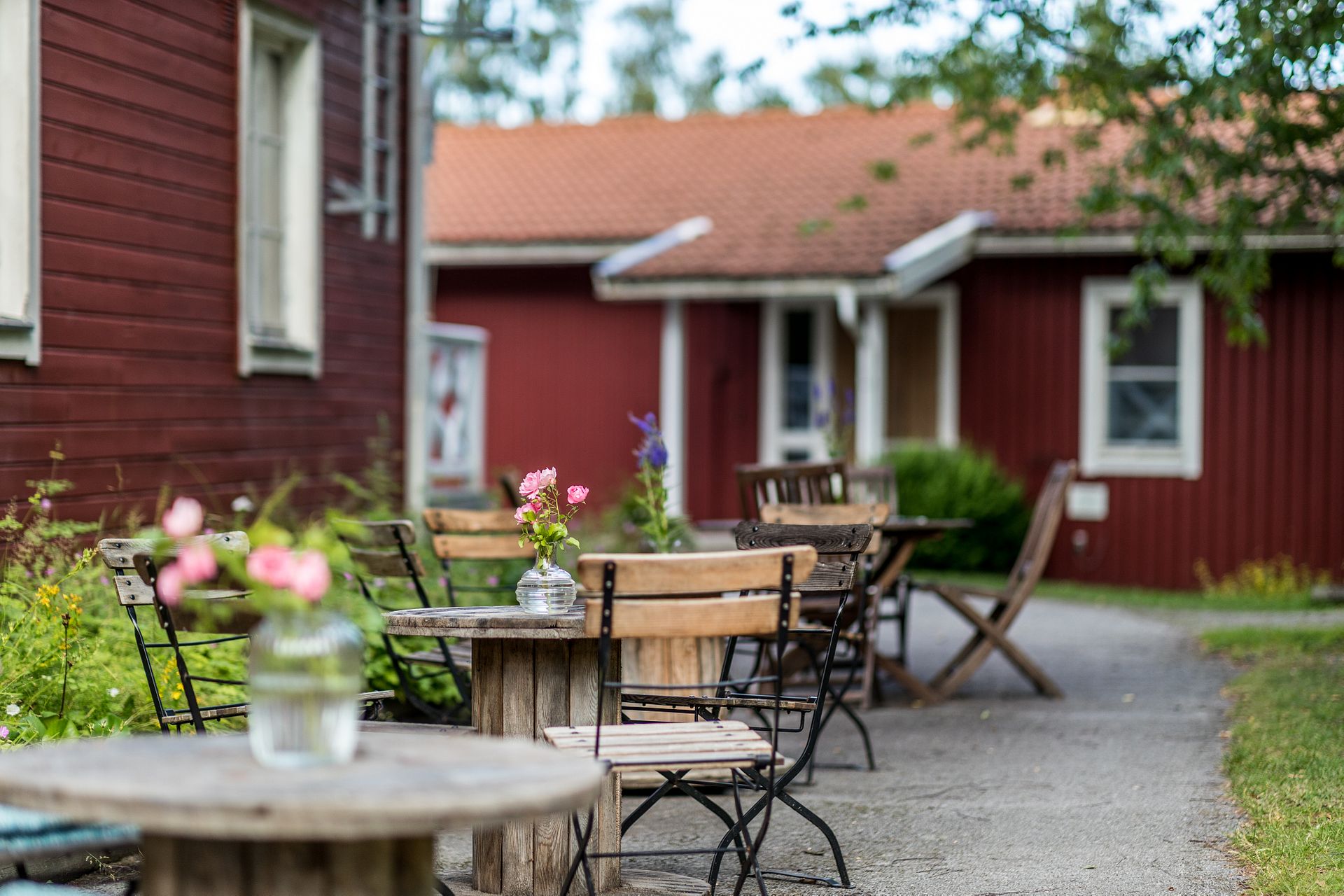 Röda hus på en gård med bord och stolar på gruset