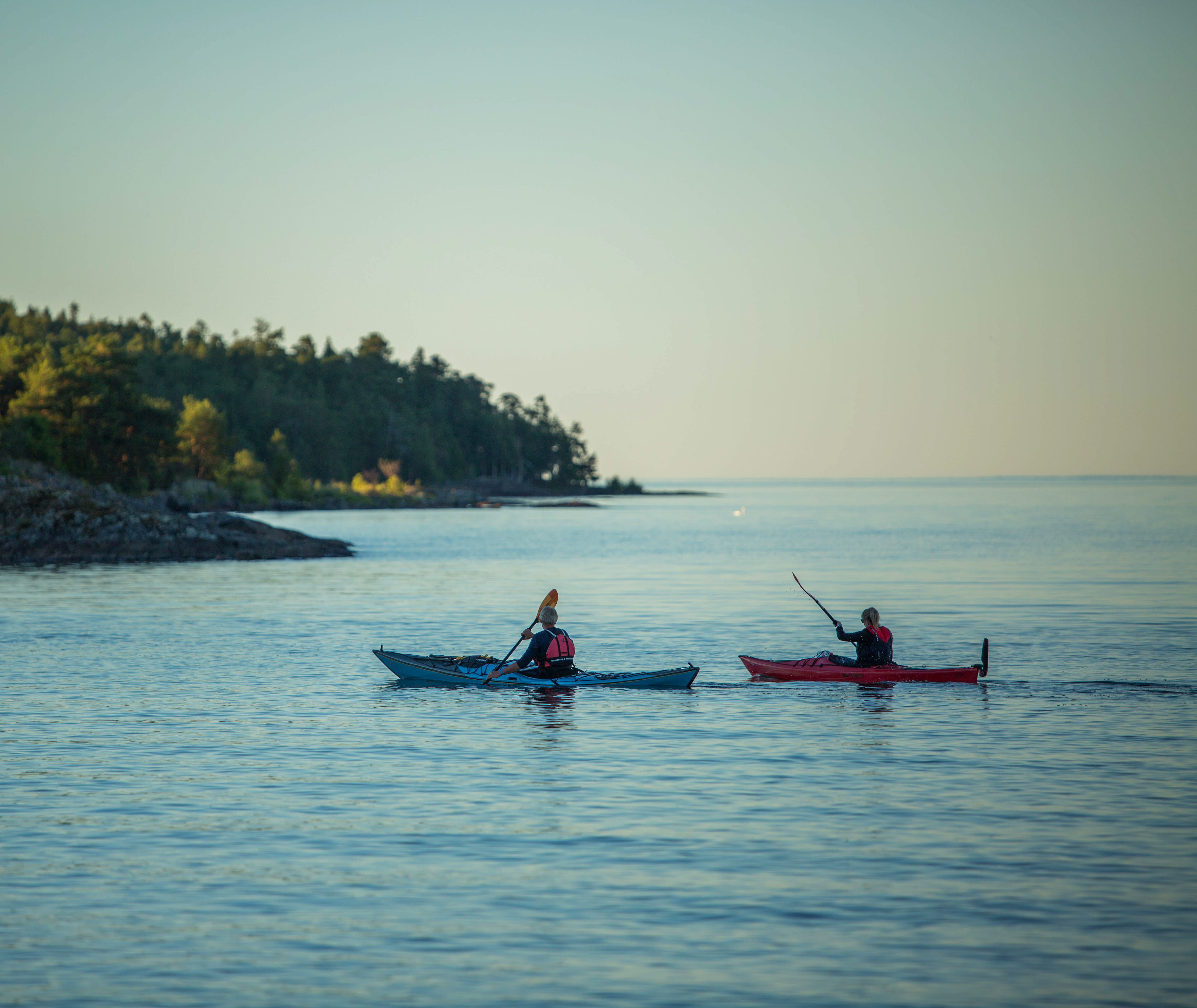 Two people kayaking on still water and summer evening.
