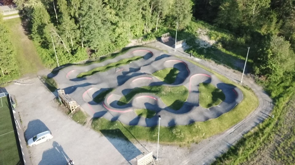 En asfalterad bana med flertal gupp. Banan omringas av skog och grönområden. 