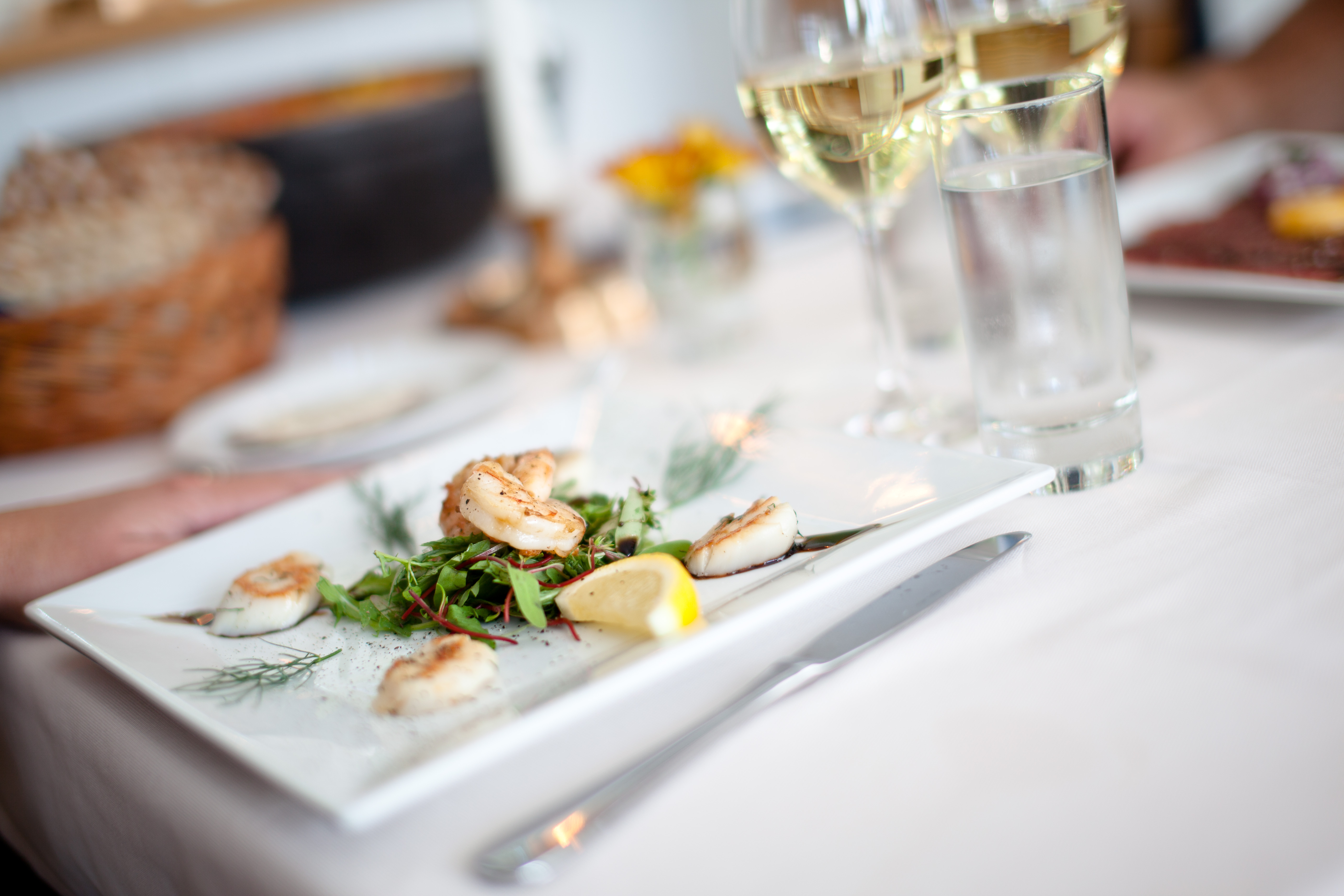 Närbild på tallrik med fint upplagd mat. Framför tallriken står ett glas champagne.