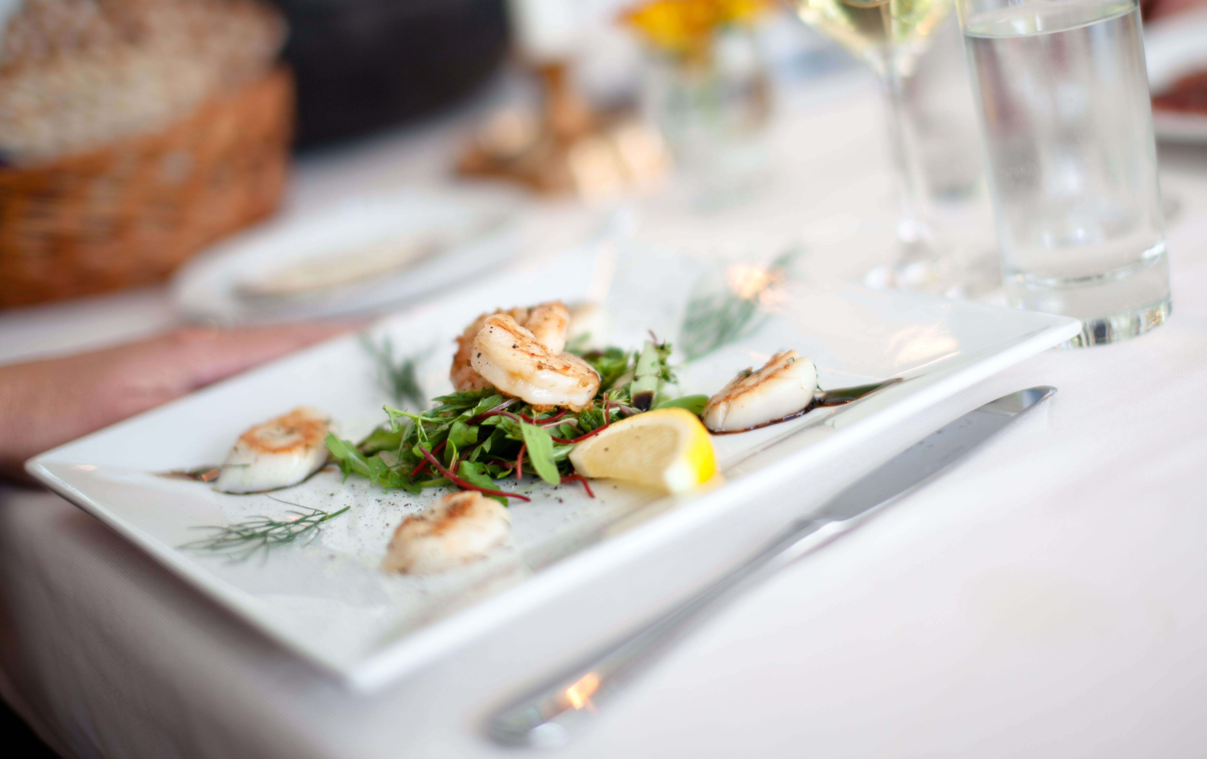 Close up of a plate with nicely presented food. In front of the plate is a glas champagne.
