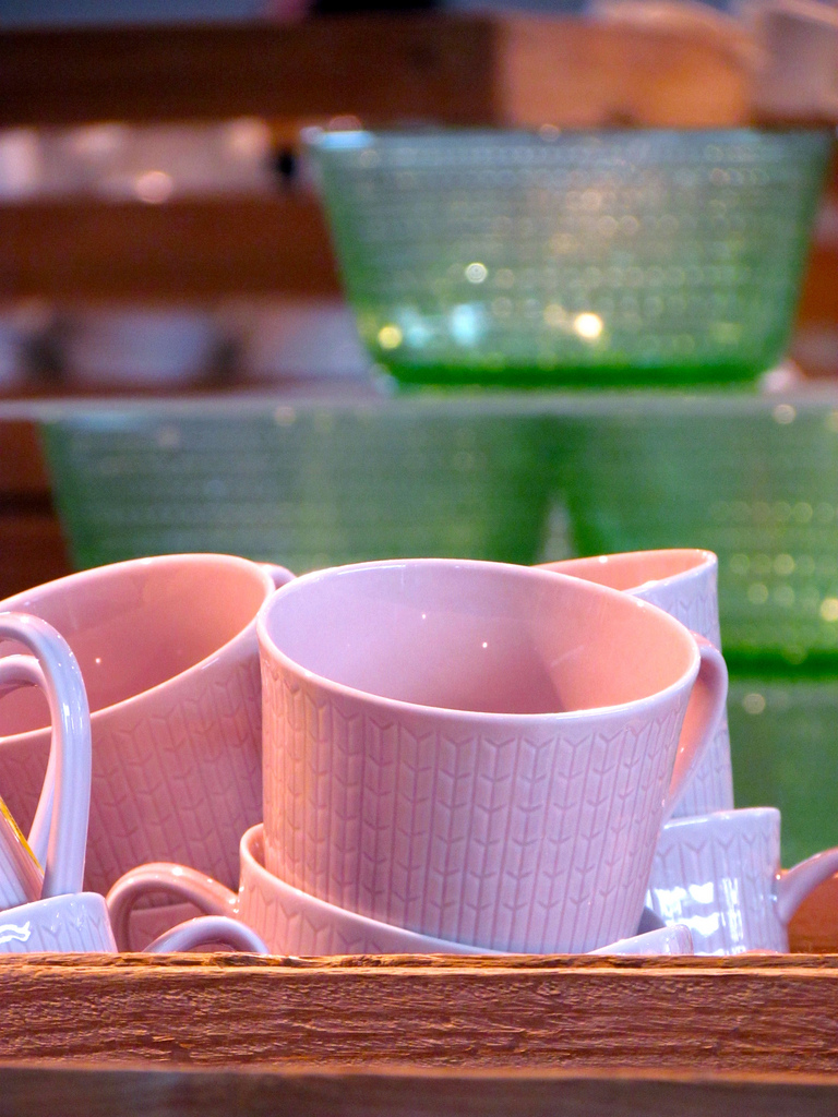 Rosa muggar och gröna skålar i en butik.