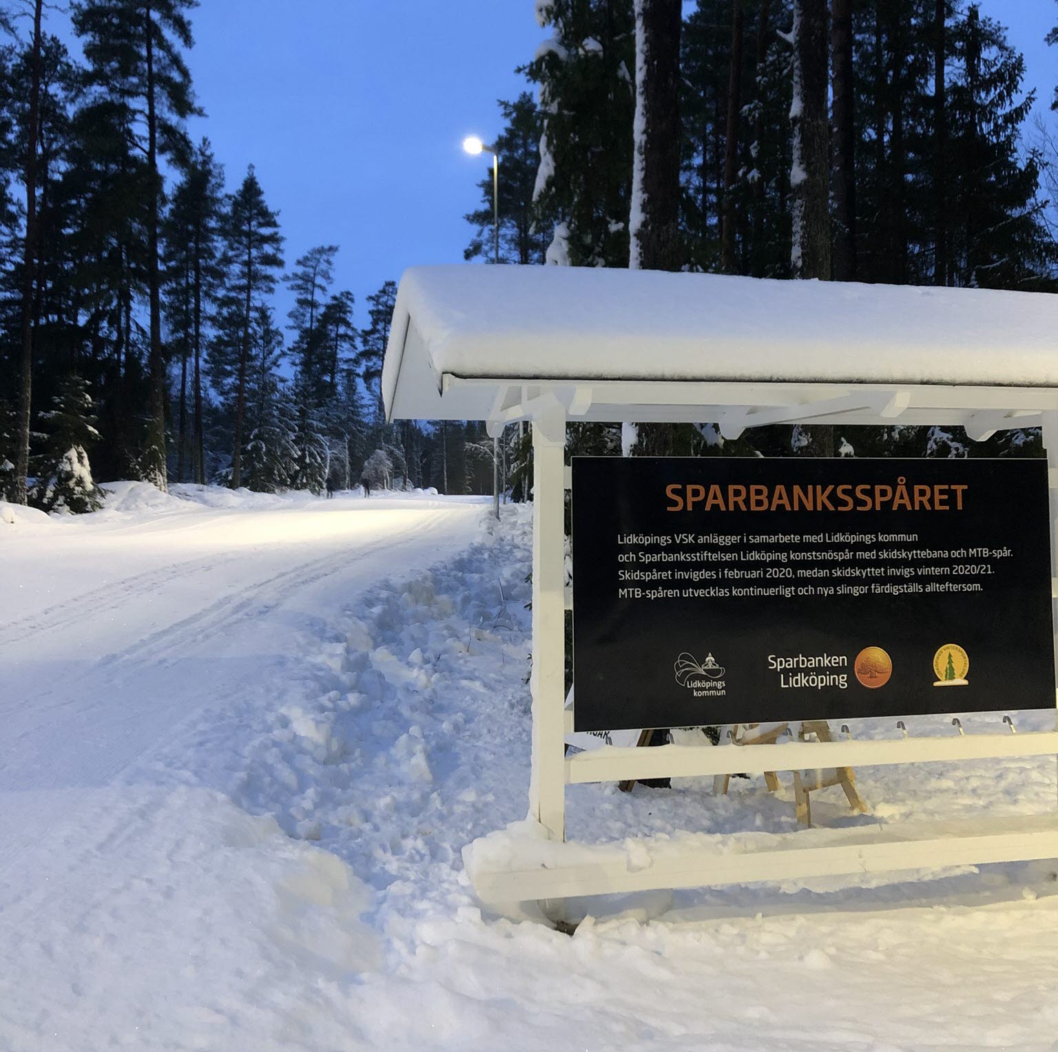 Skylt vid starten av Sparbanksspåret, en längdskidanläggning. Marken är täckt av snö.