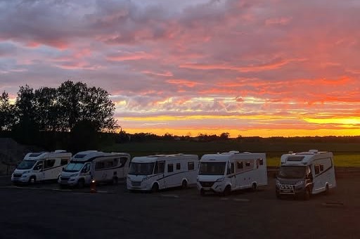 Solnedgång med fem husbilar uppradade i förgrunden