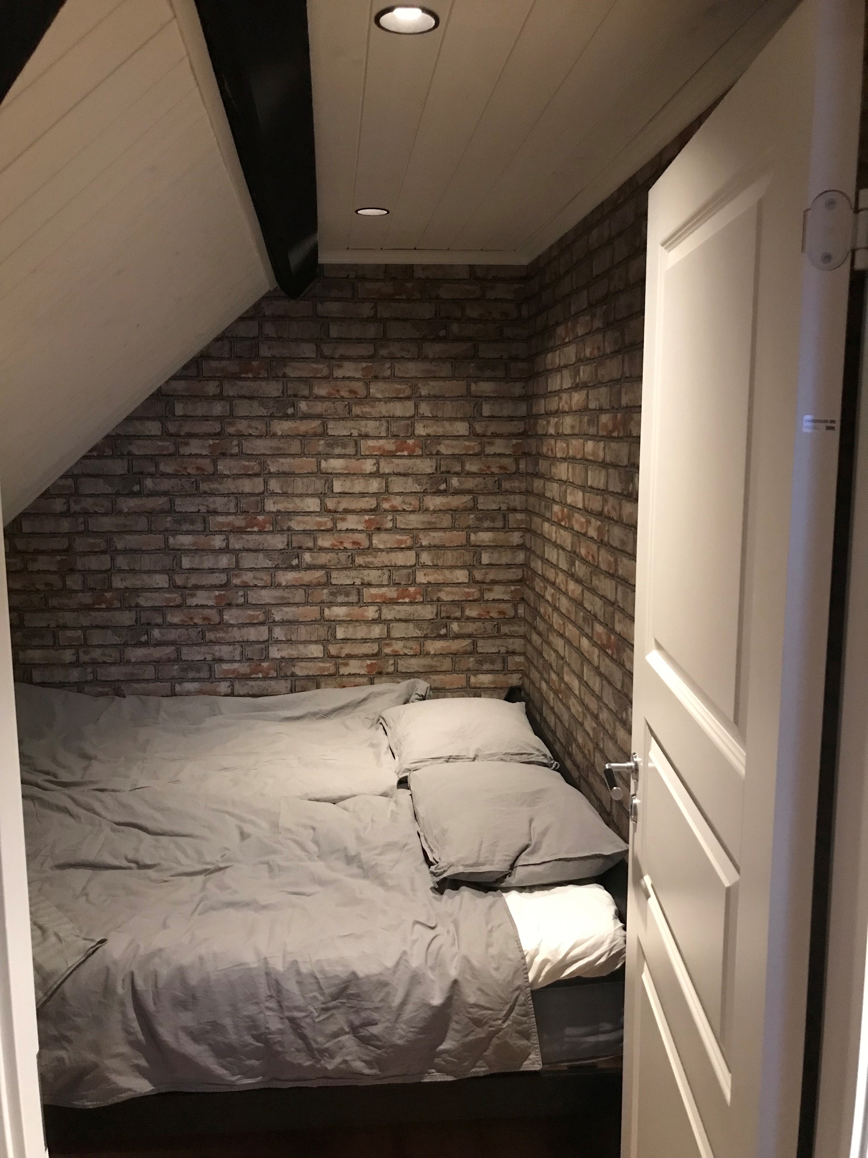Mysigt sovrum med tegel på väggen och snedtak.