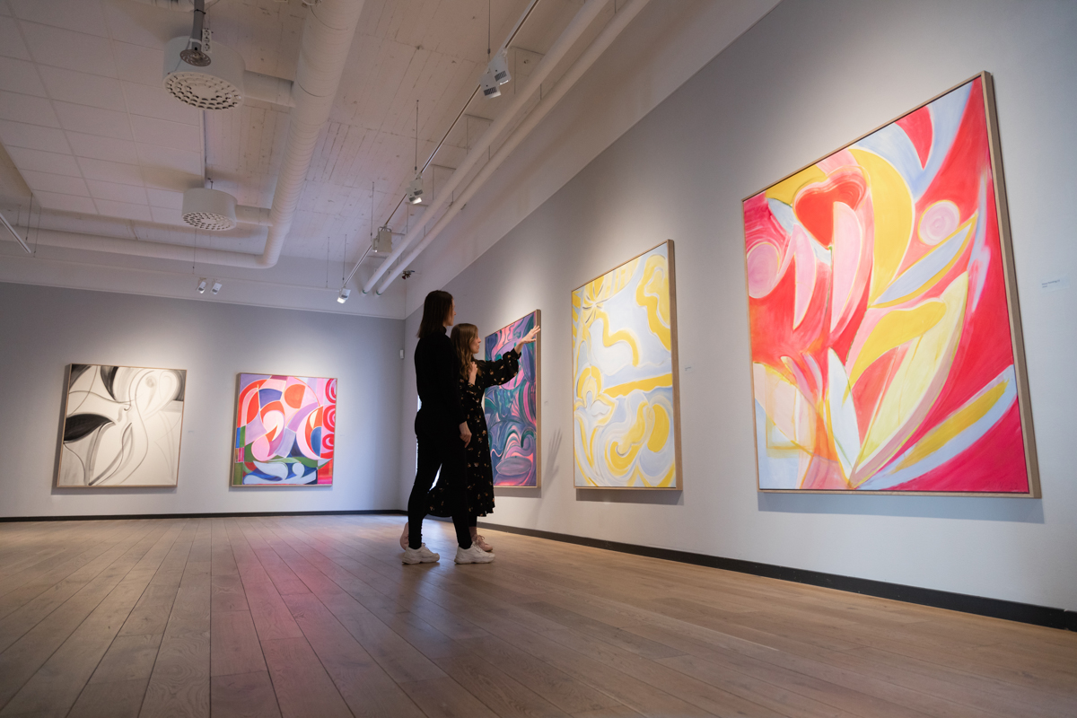 Två kvinnor kollar på färgglad konst. 