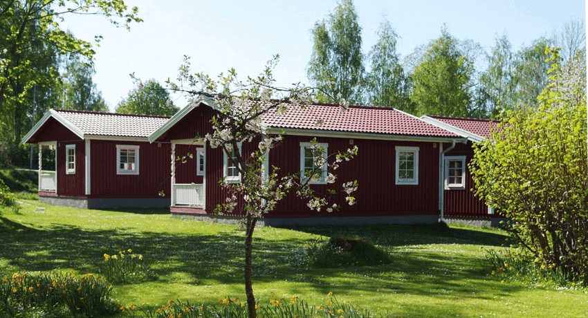 Två röda stugor i grönskande natur