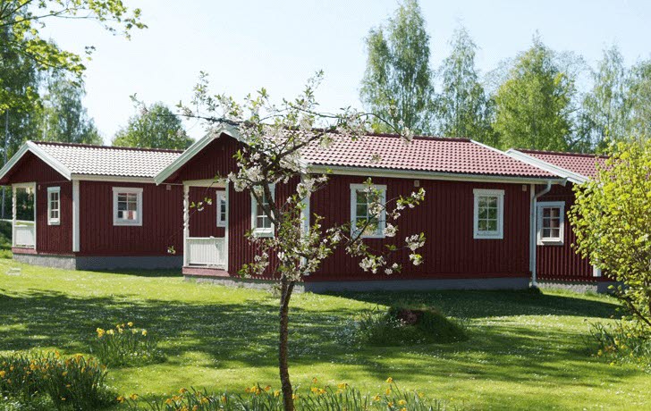 Två röda stugor i grönskande natur