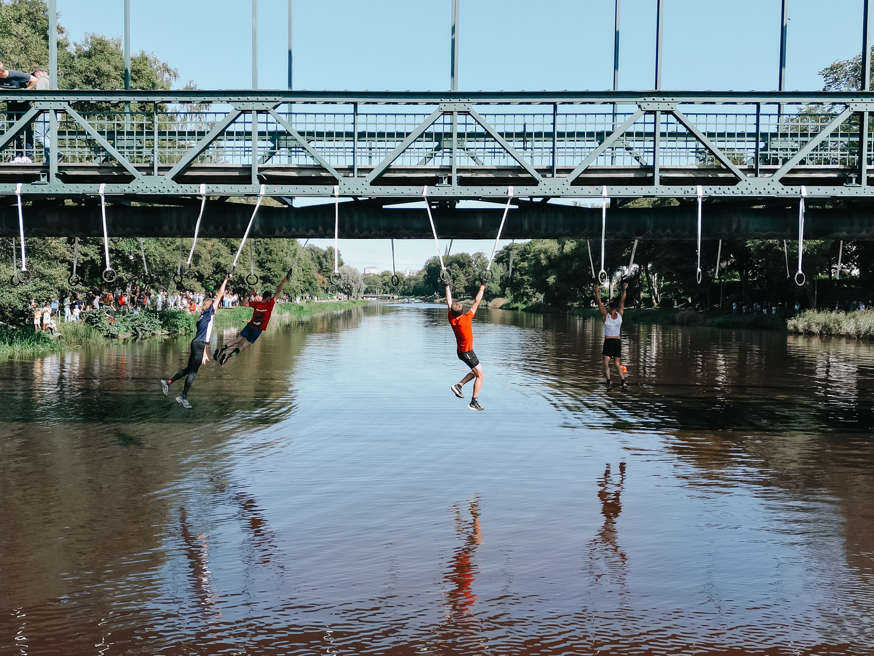 Personer som svingar i ringar under en bro över Lidan, de tävlar i hinderbaneloppet The Obstacle Run.