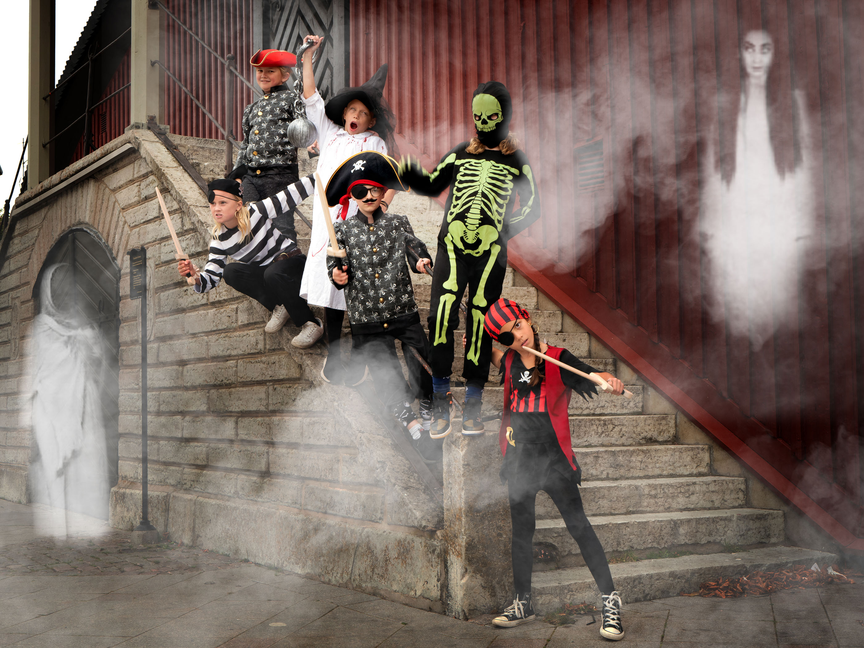Ett gäng barn som är utklädda till gastar och sjöbusar står i en trappa utomhus. Runt dem flyger två spöken.