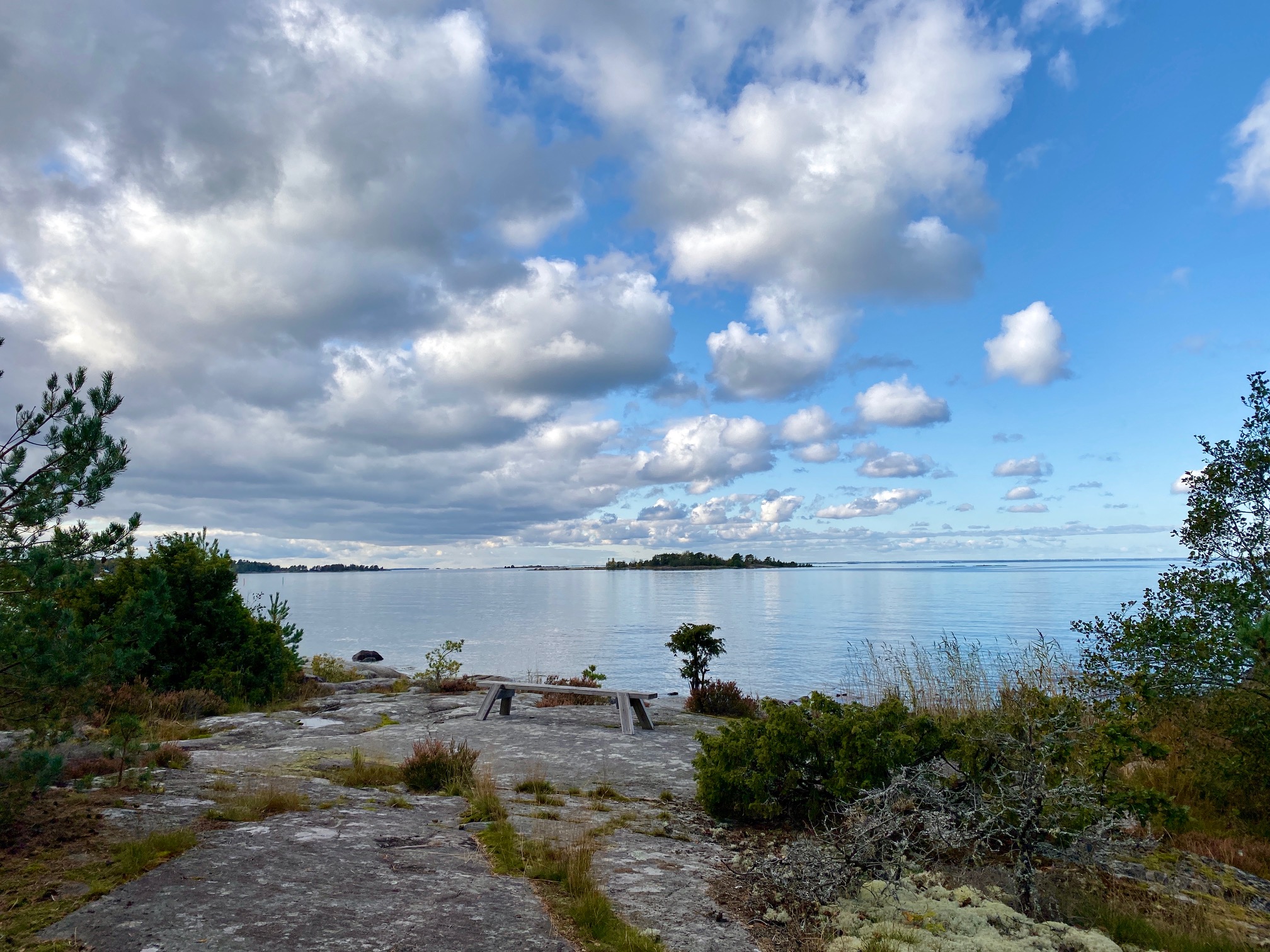 View of Lake Vänern from a cliff with a park bench.