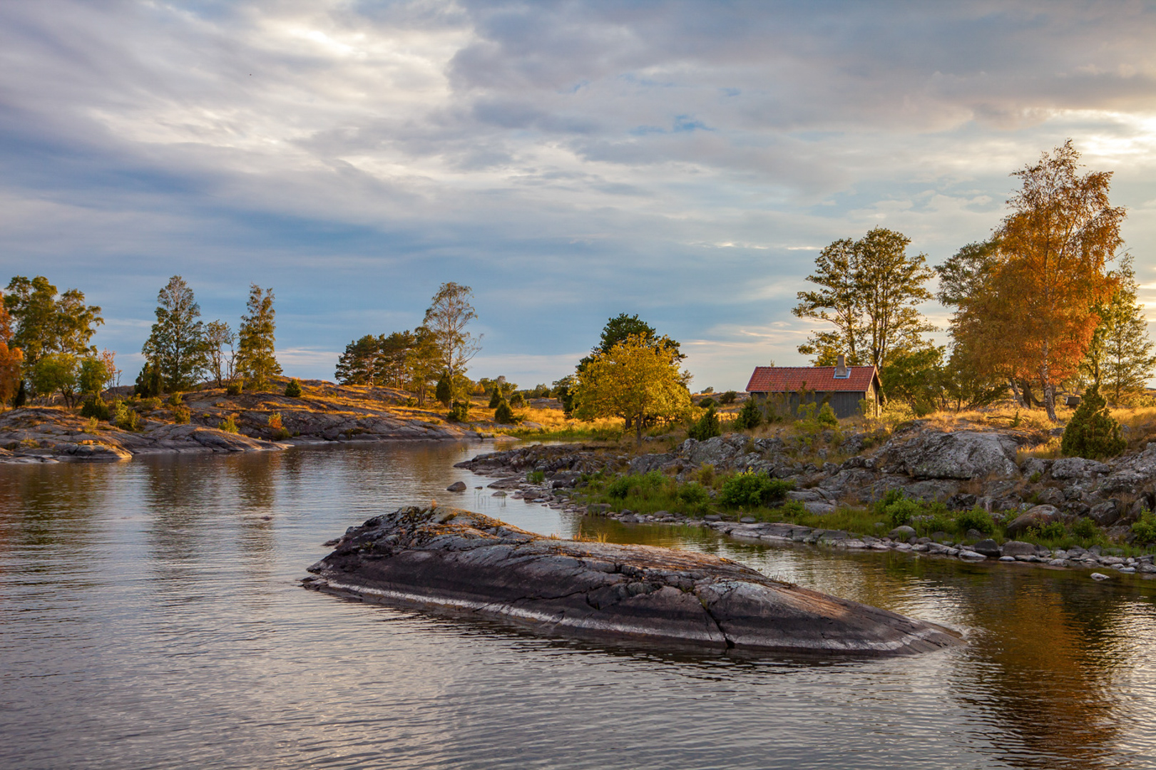 The archipelago of eken in the lake of Vänern. Warm light on the cliffs by the water, a summer evening.