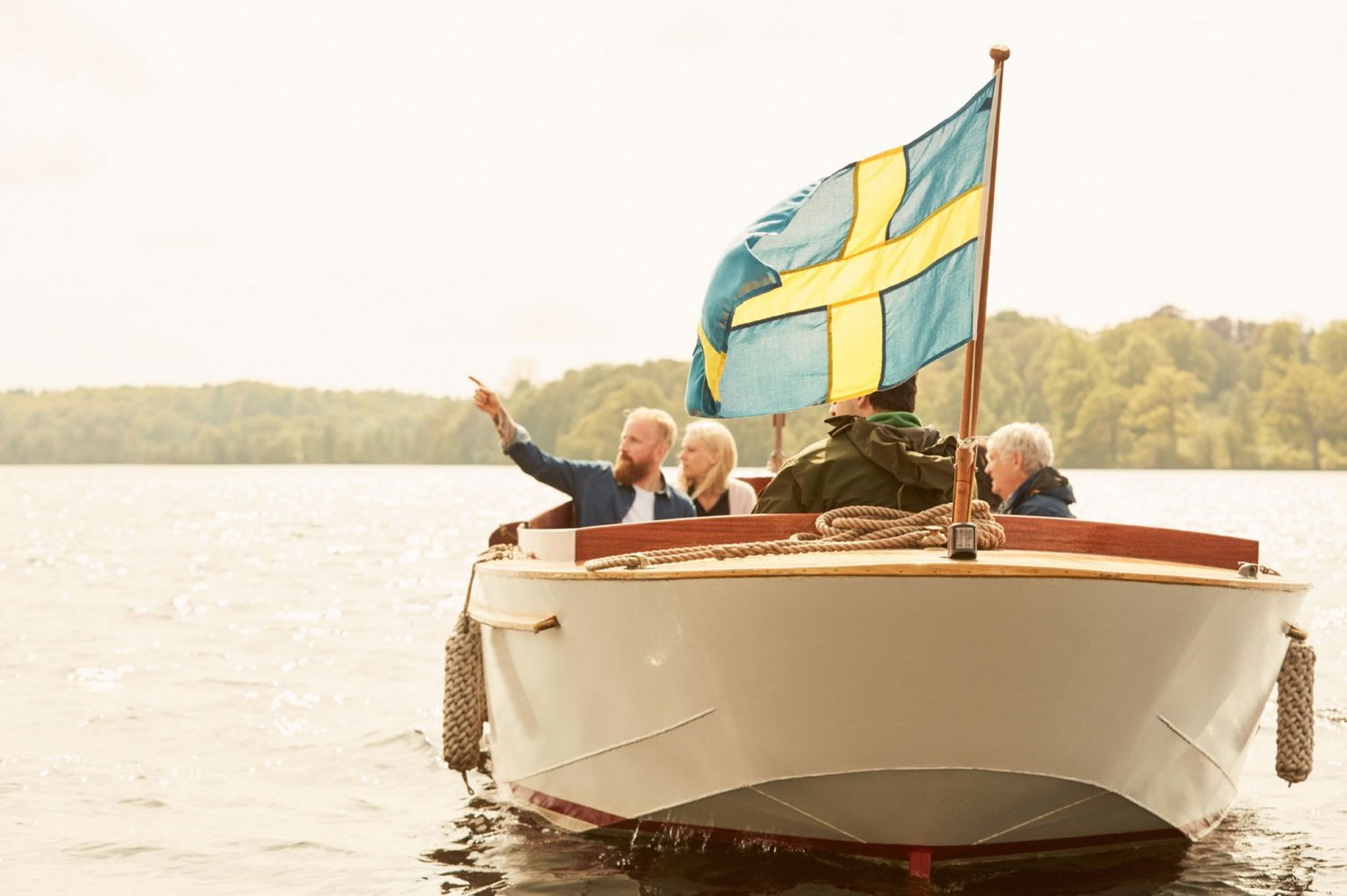 folk i båt med svensk flagga