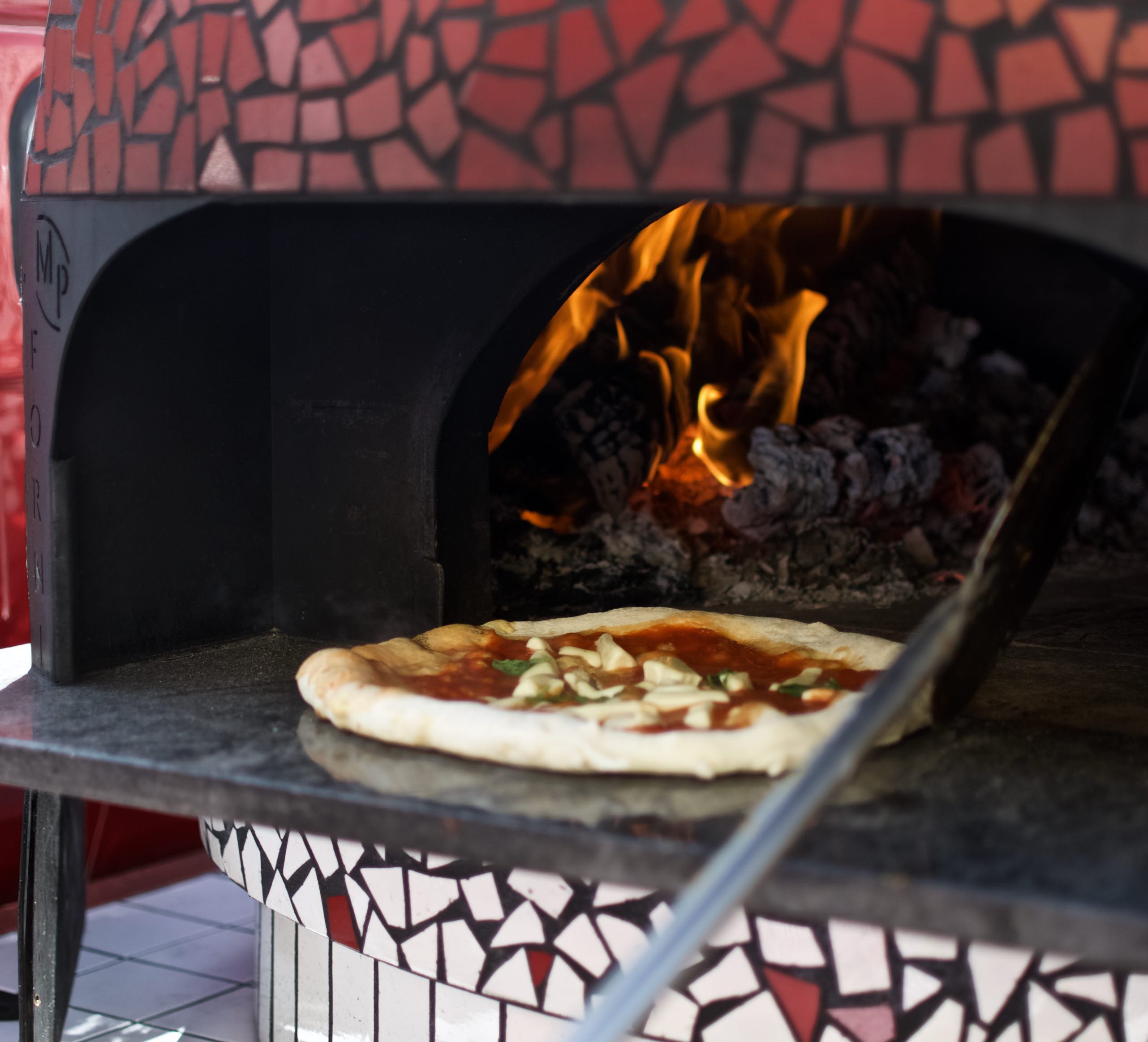 Red pizza oven with pizza inside, un limone