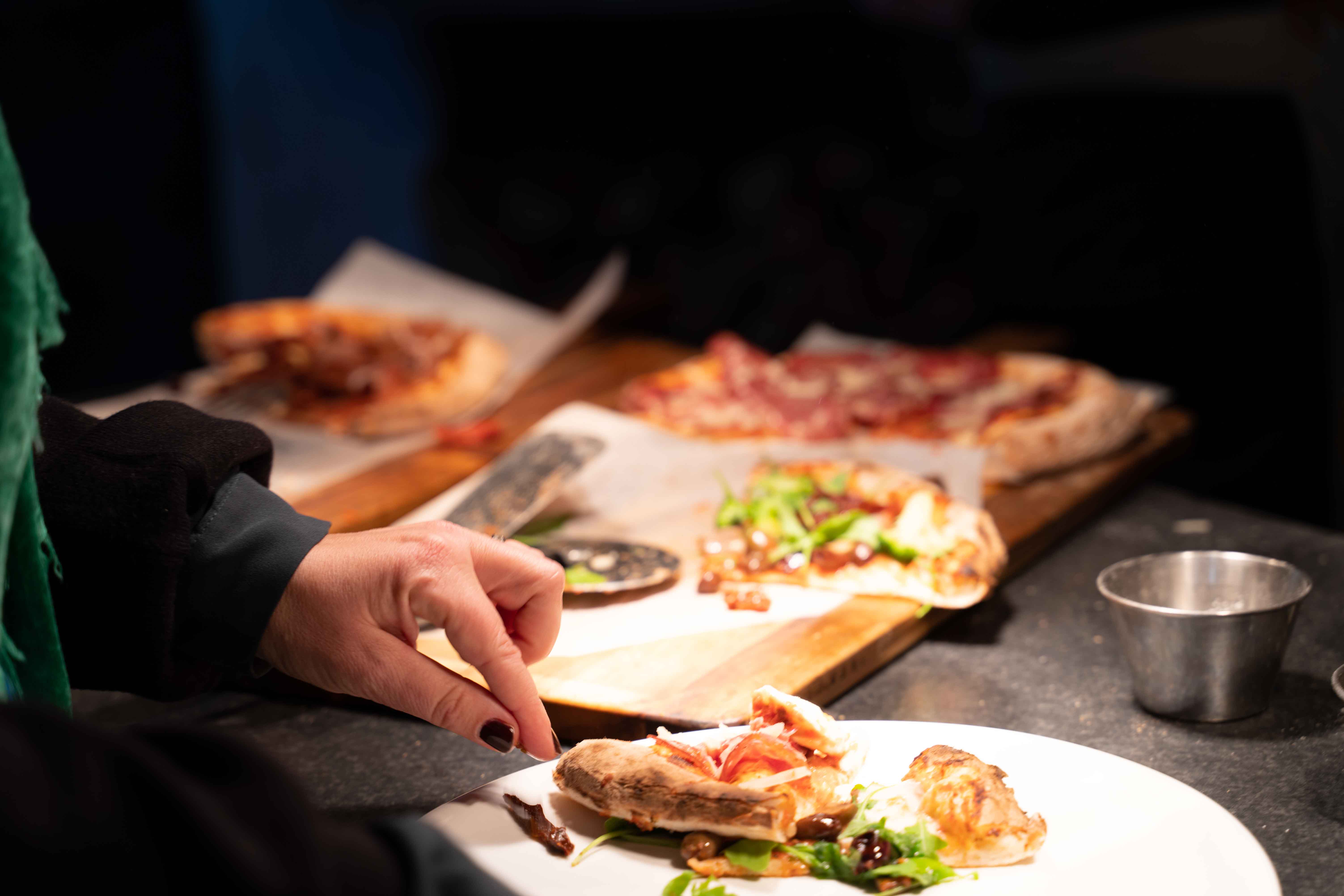 pizza on plate with hand taking a piece 