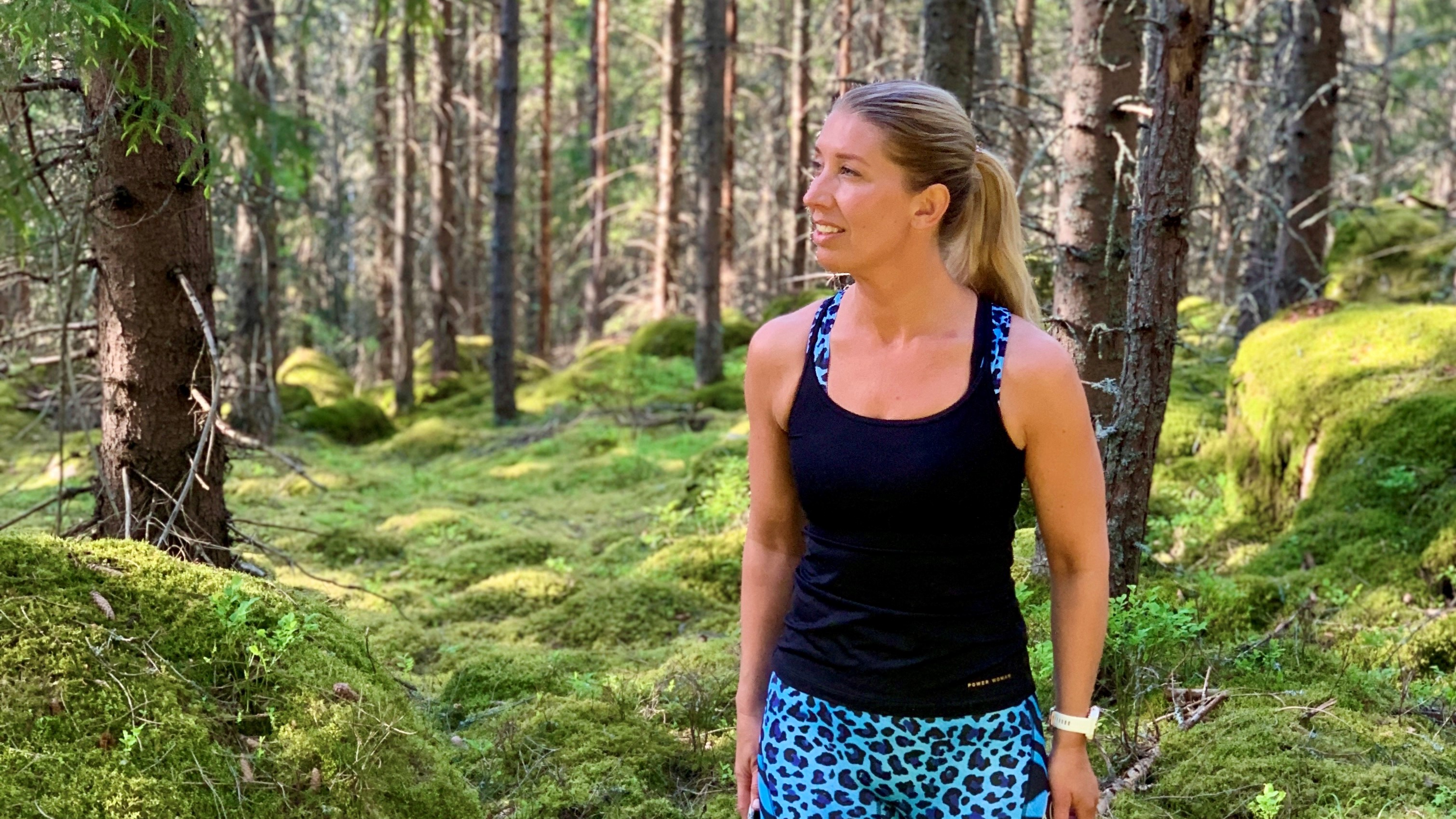 kvinna som står i grön skog sommartid