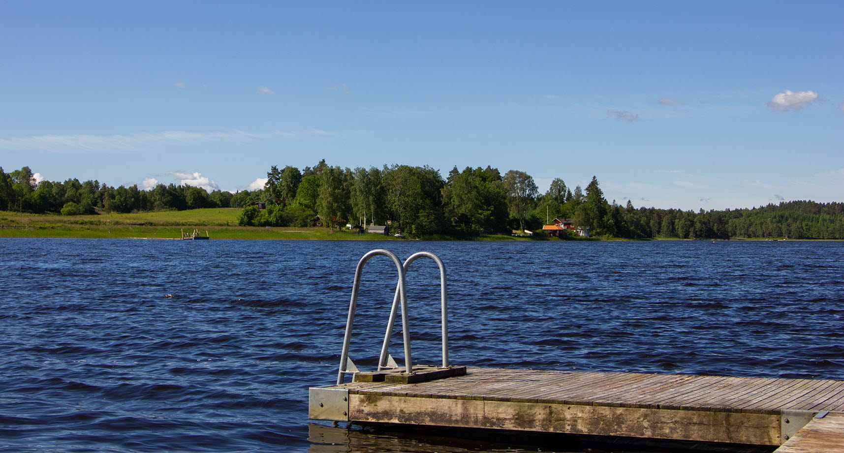 Badstege ner i blå sjö en sommardag