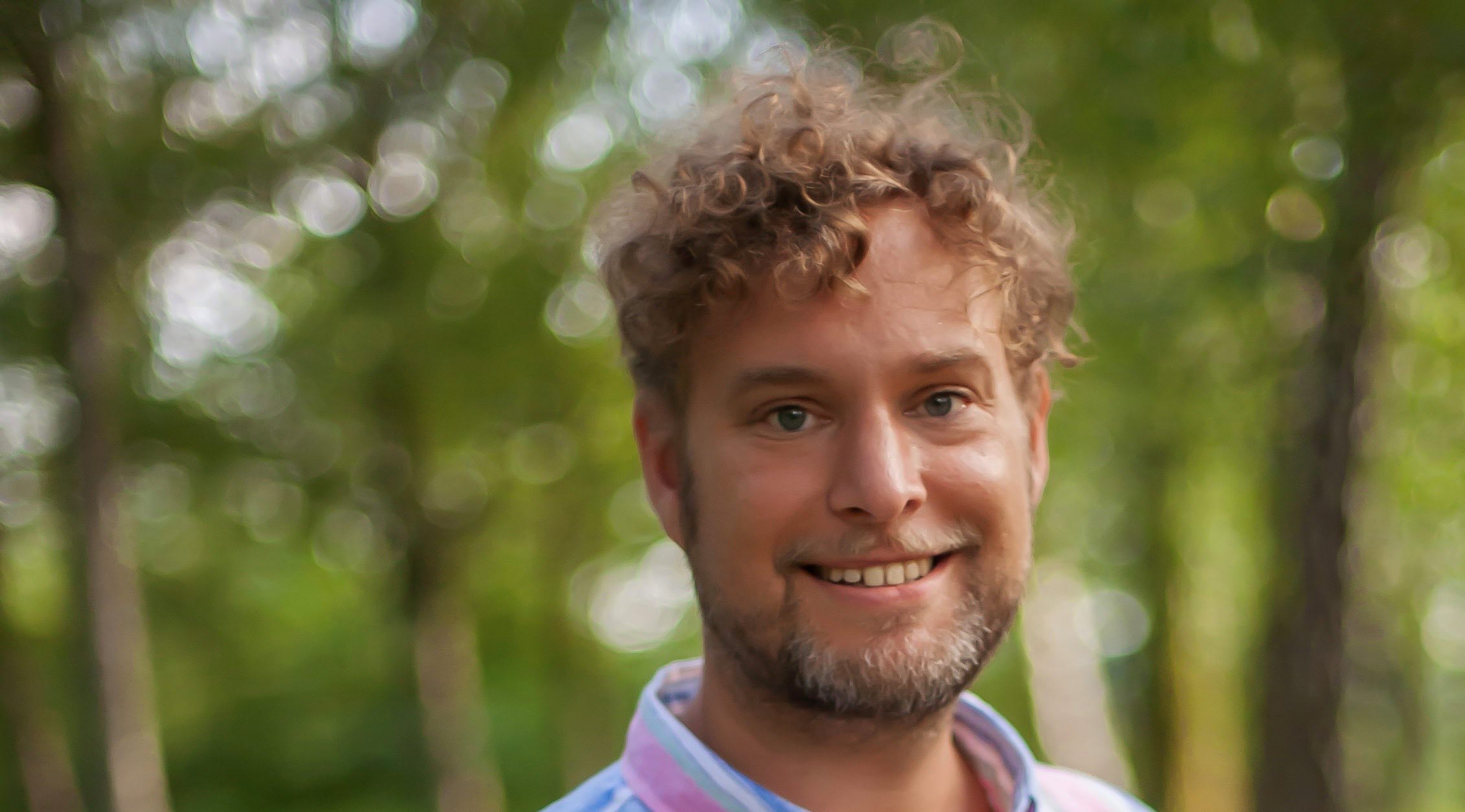 Man med lockigt hår i randig skjorta