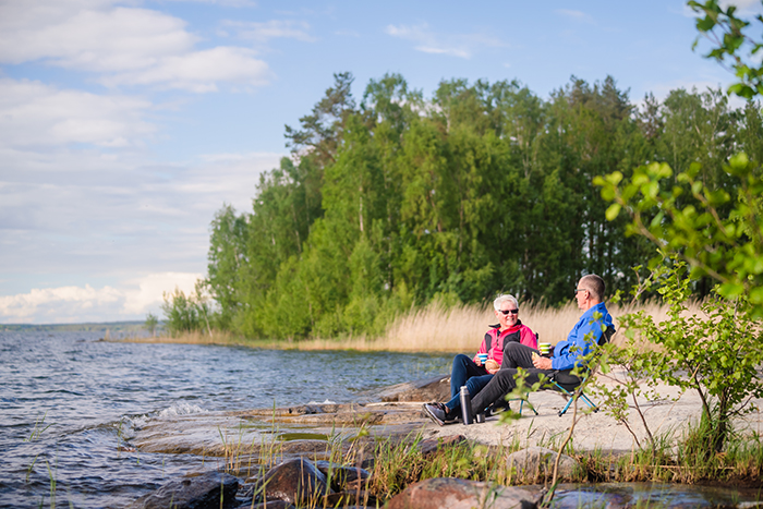 Två personer sitter i varsin campingstol på en klippa vid vattnet.