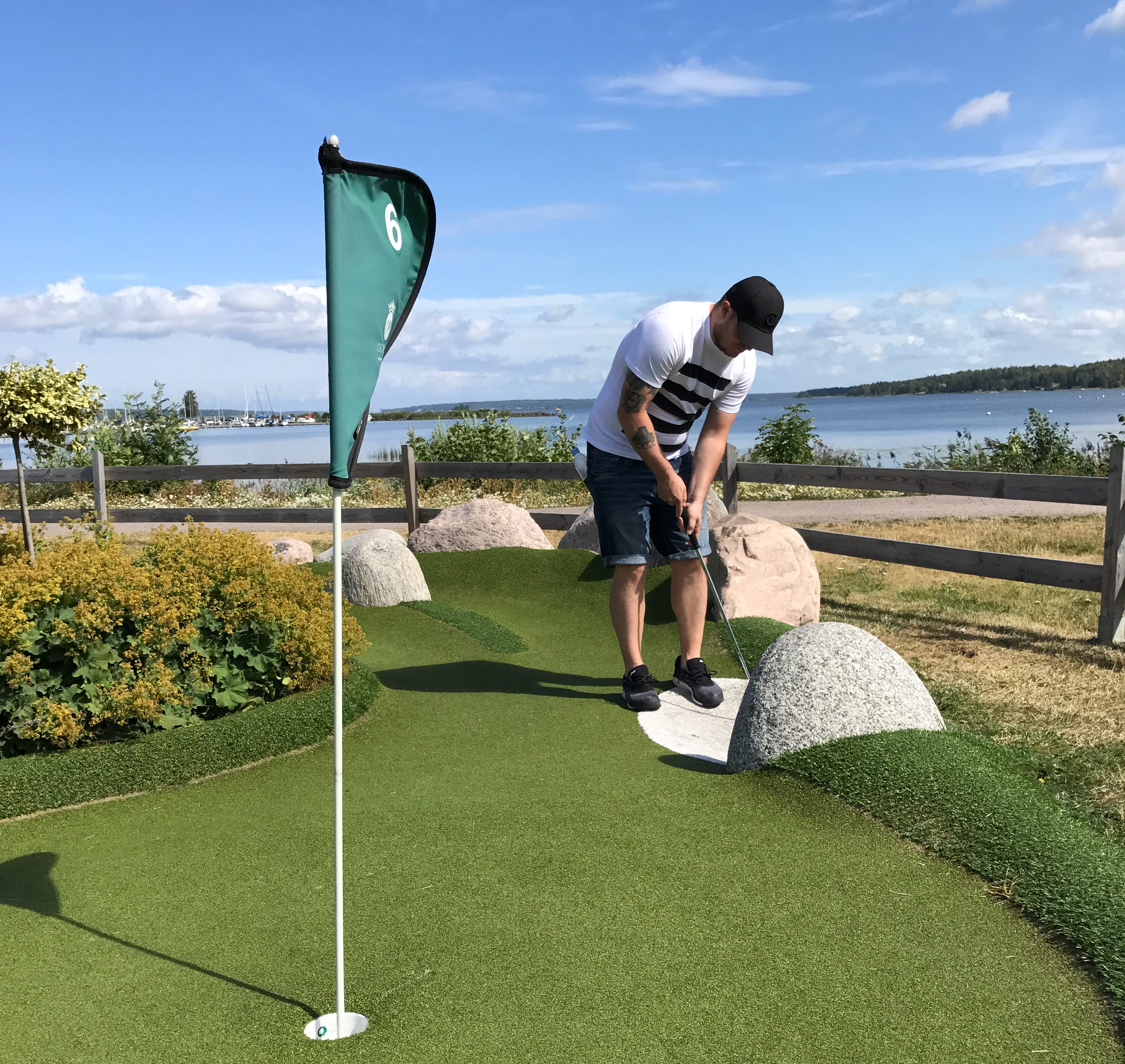 En person spelar äventyrsgolf i hamnen i Mariestad. Utsikt över Vänern i bakgrunden.