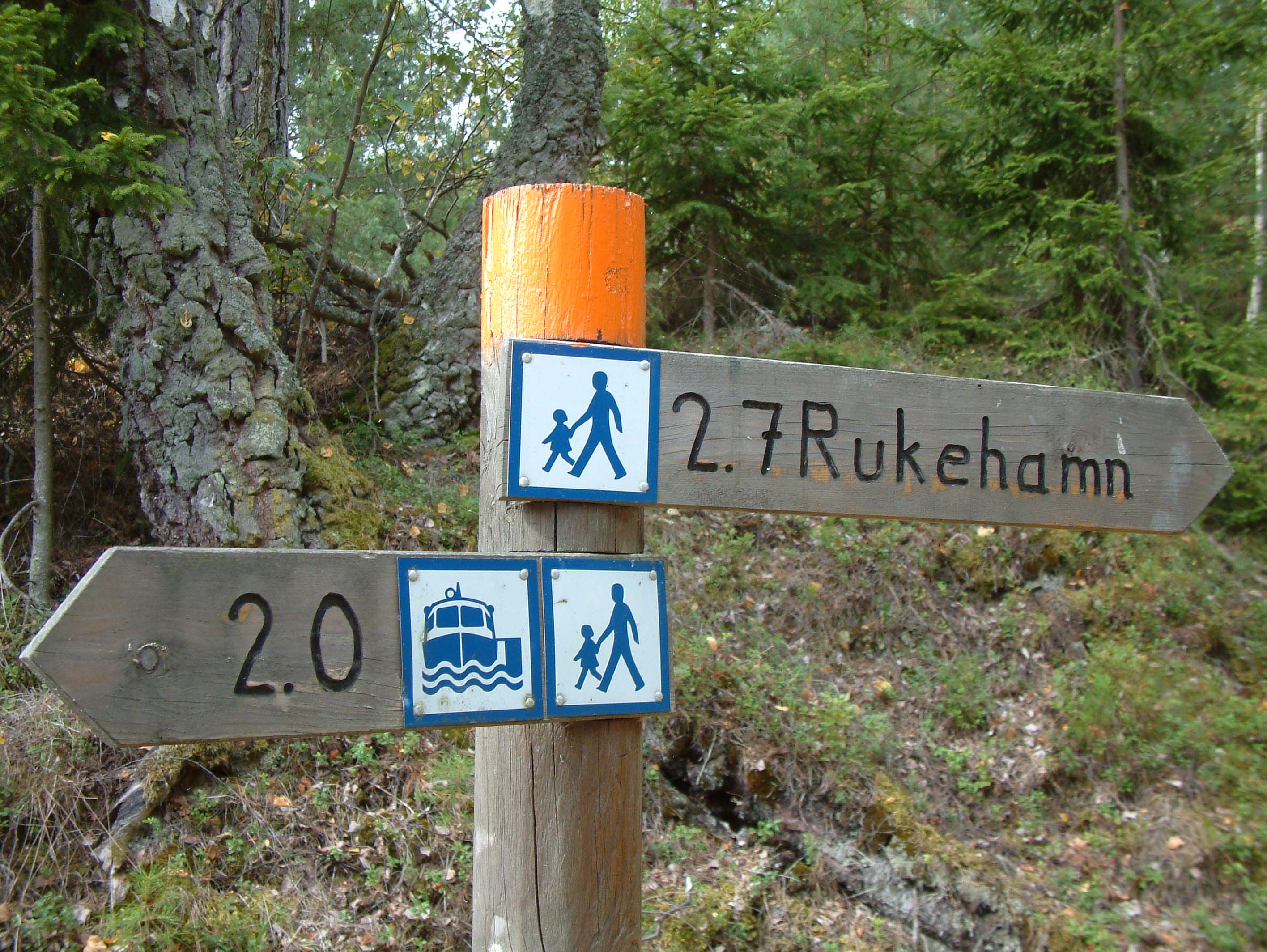 Skyltar som pekar till vandring, bad och färjeläget på Brommö i Mariestads skärgård. 