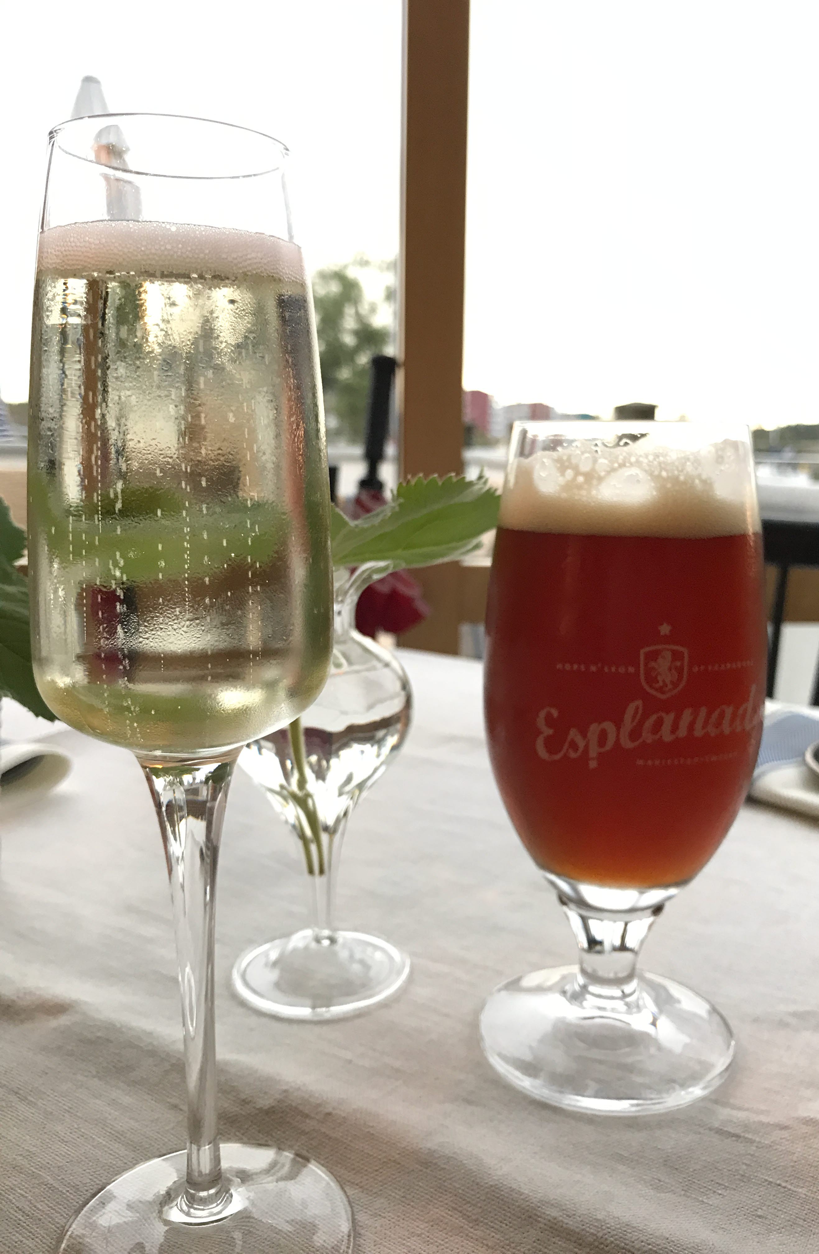 Ett glas bubbel och ett glas öl på ett bord. 