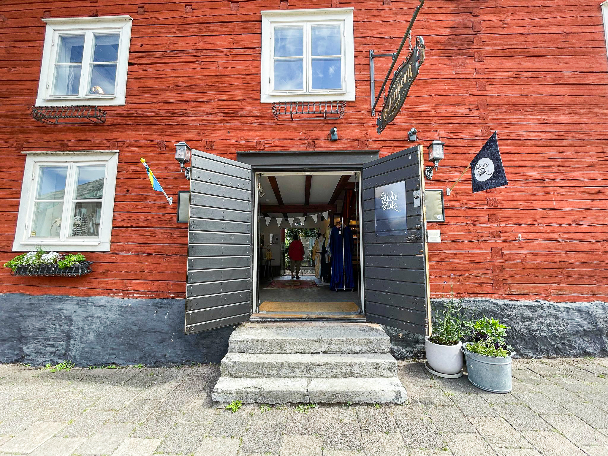 Red wooden house with open doors towards the street.