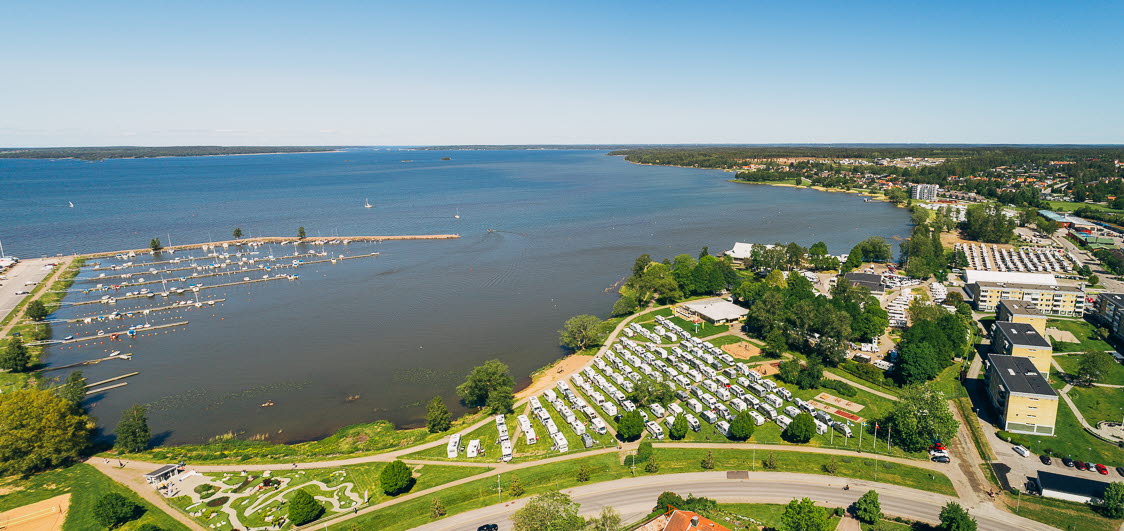 Panorama över Karlsholme i Mariestad med Vänern i bakgrunden och husbilar i rader uppställda vid Husbilsklubbens årsmöte. 