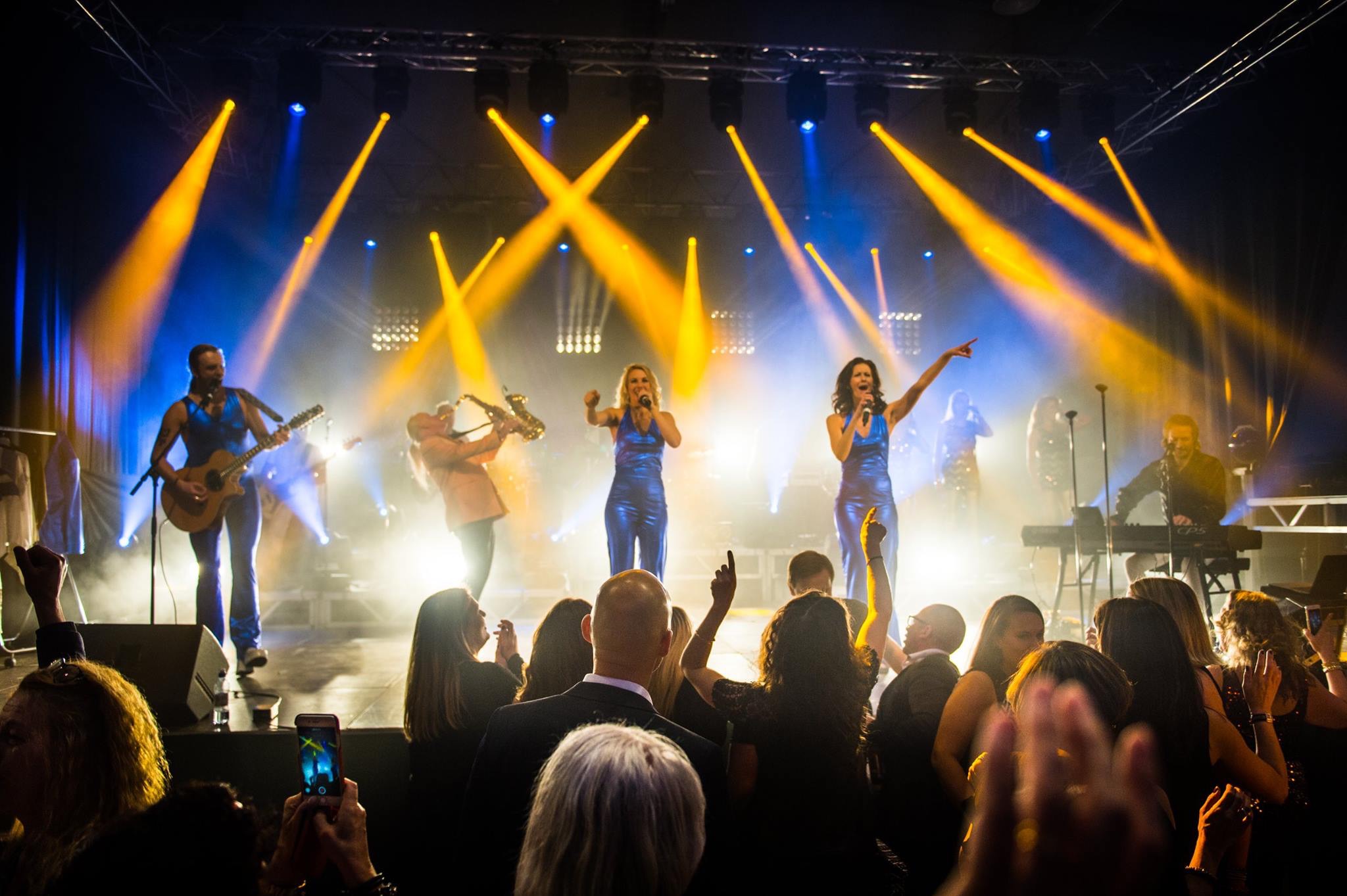 ABBA-show på scenen med publik i förgrunden.
