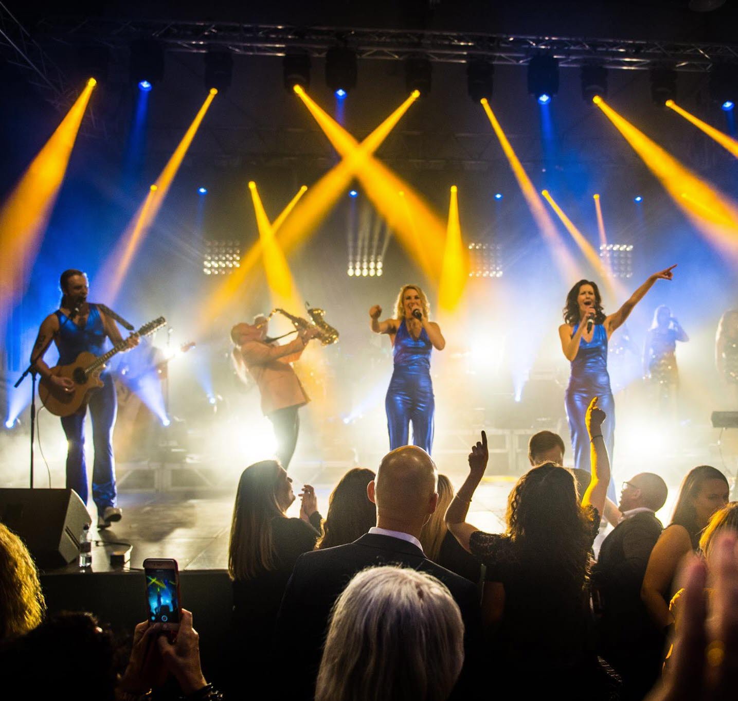 ABBA-show på scenen med publik i förgrunden.