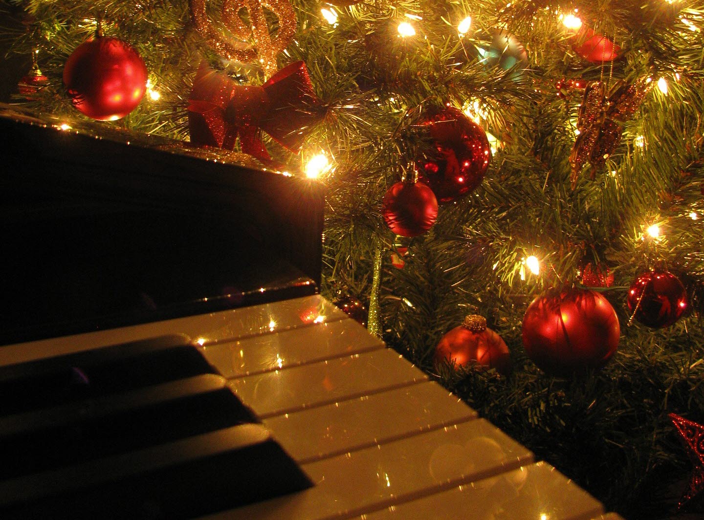 Julpyntad gran med en del av ett piano i förgrunden.