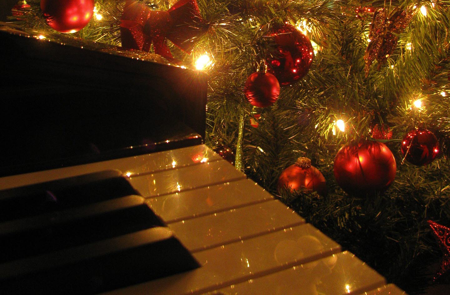 Julpyntad gran med en del av ett piano i förgrunden.