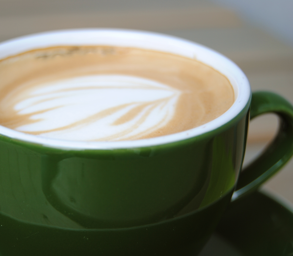 En grön kopp med cappuccino.