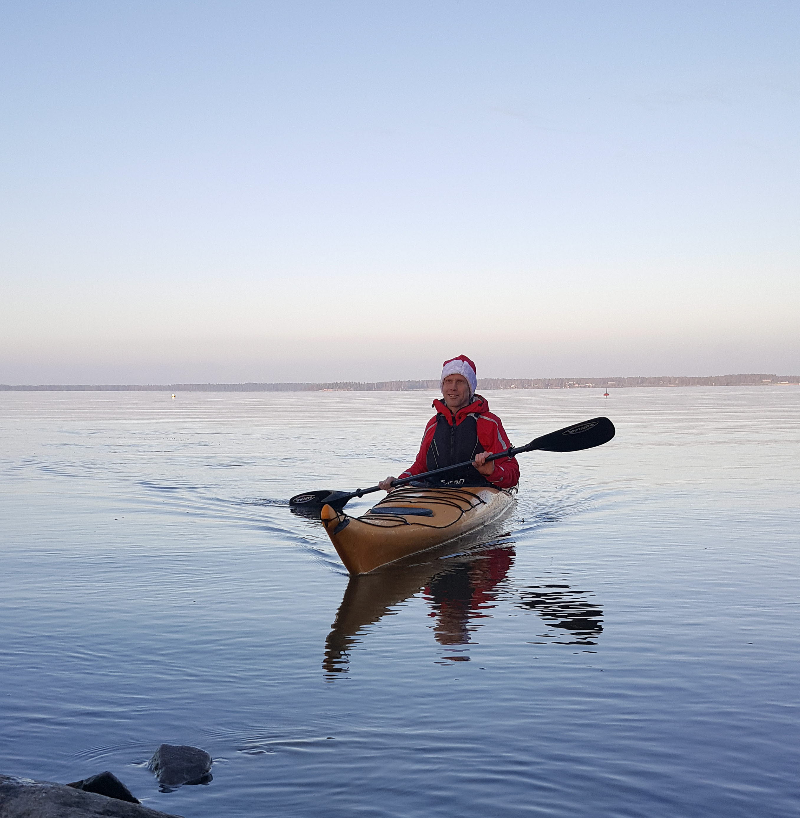En person i tomteluva paddlar kajak.