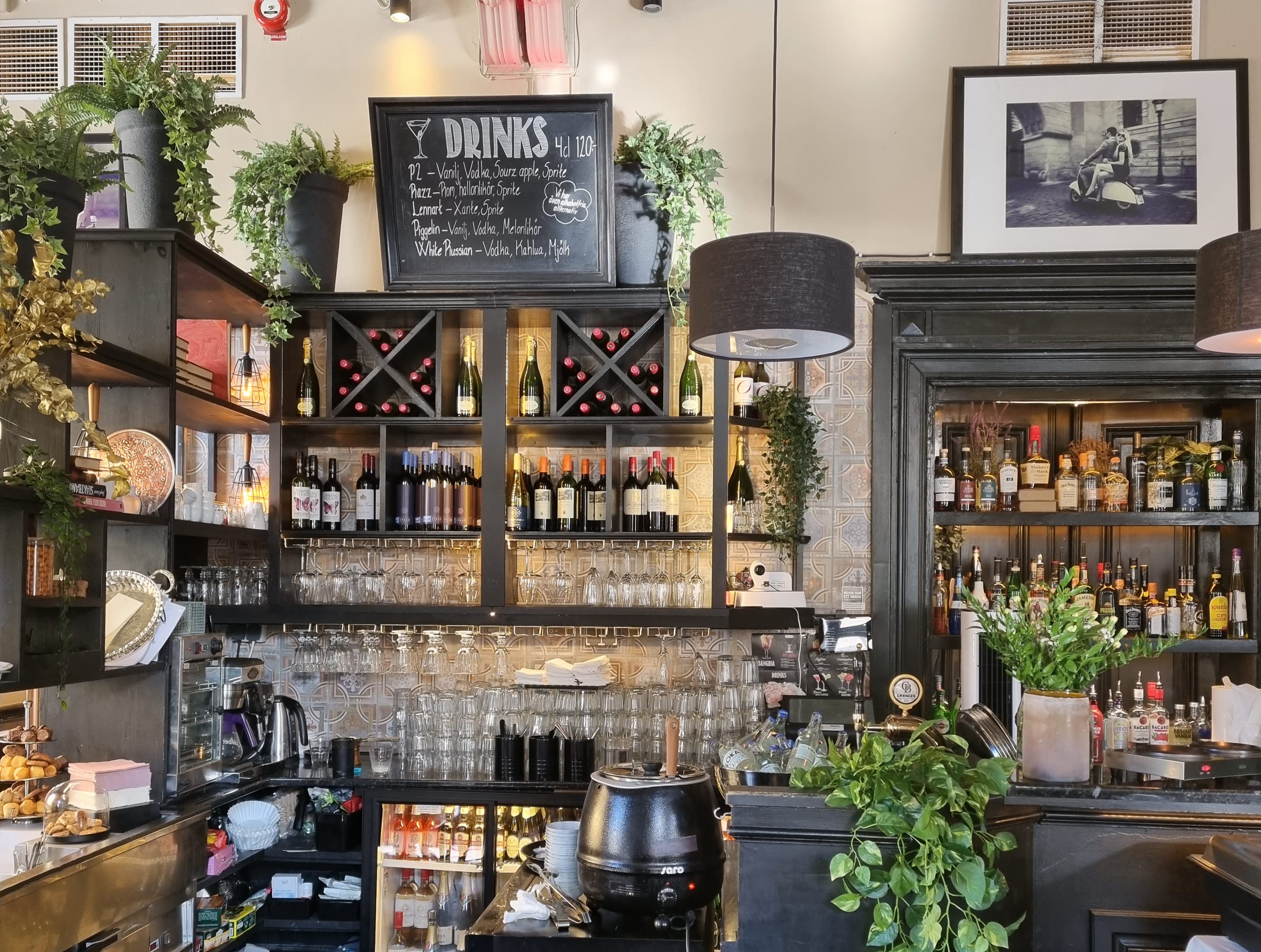 Baren på restaurang, med glas, flaskor och drinkmeny på griffeltavla.