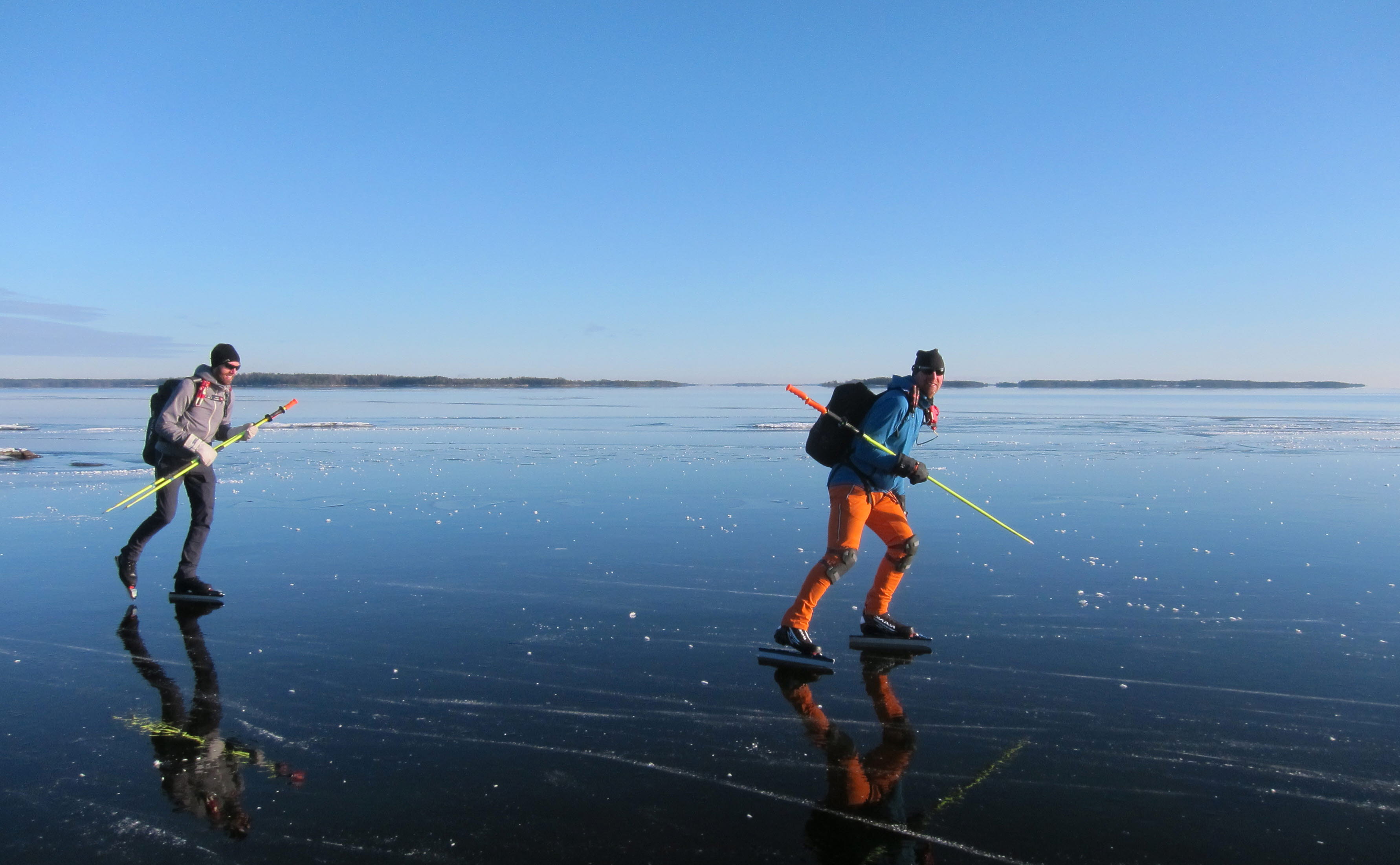 Två personer åker skridskor på en frusen sjö.