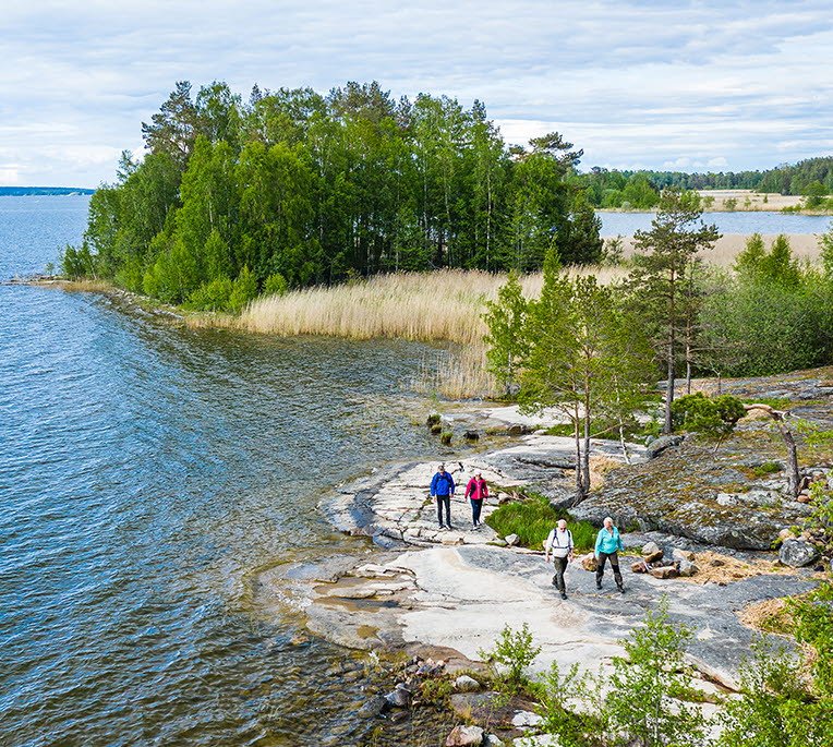Fyra personer vandrar på klippor vid Vänern, på vandringsleden Ekudden-Sandviken i Mariestad.
