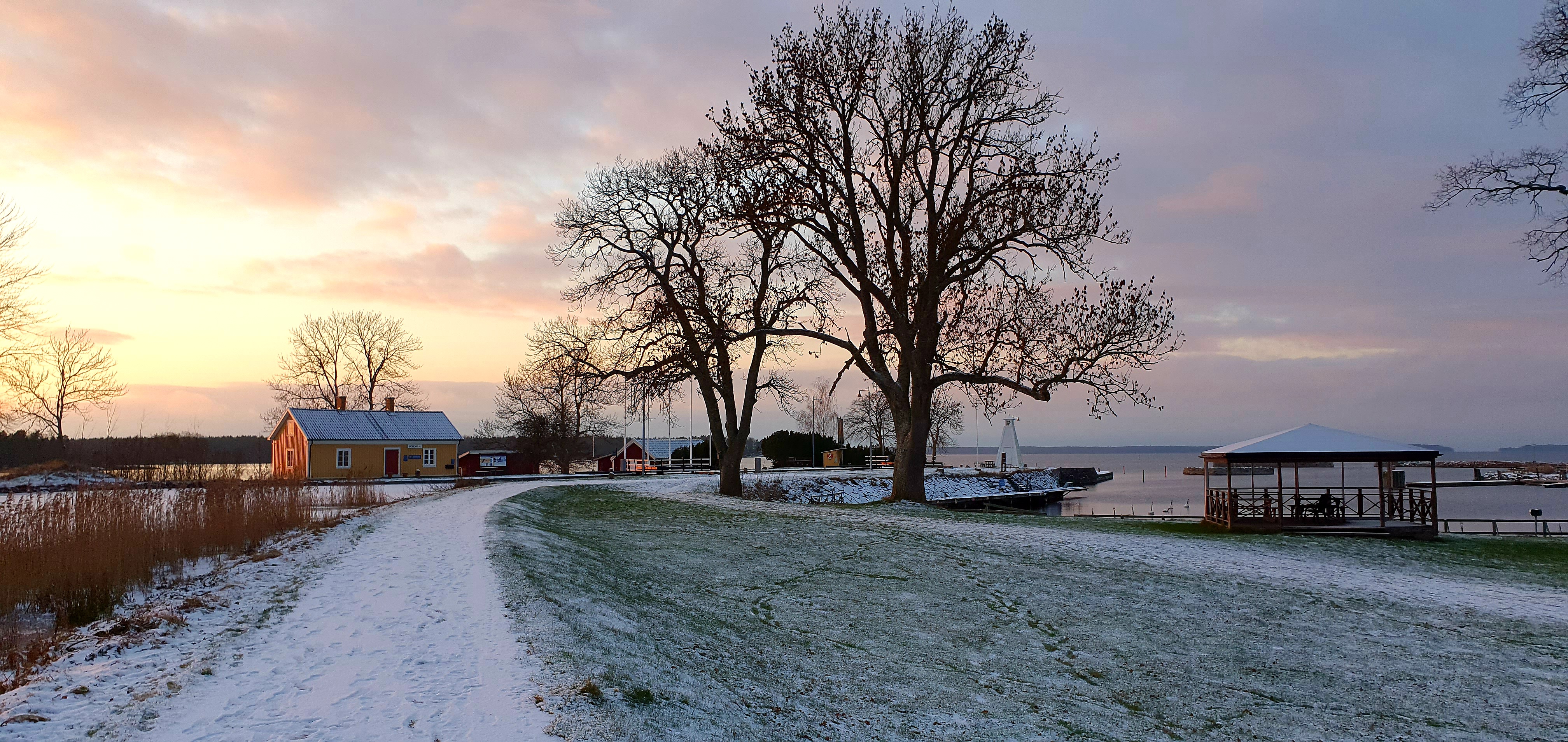 Snöigt längs Göta kanal i Sjötorp med solnedgång i Vänern i fonden.