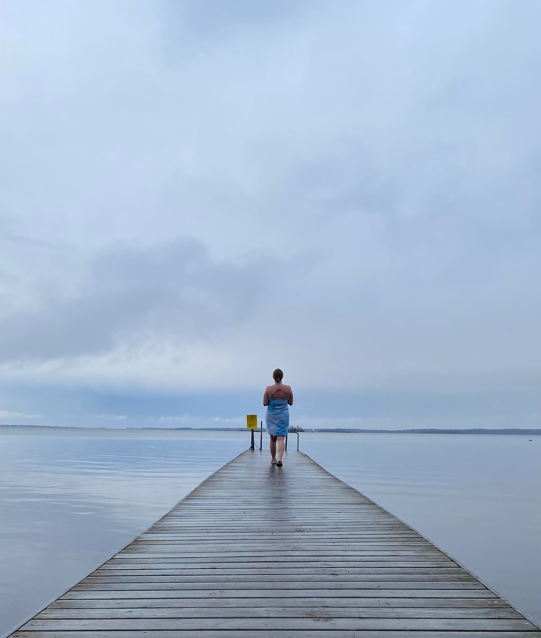 En person går på en brygga på en handduk virad om kroppen.