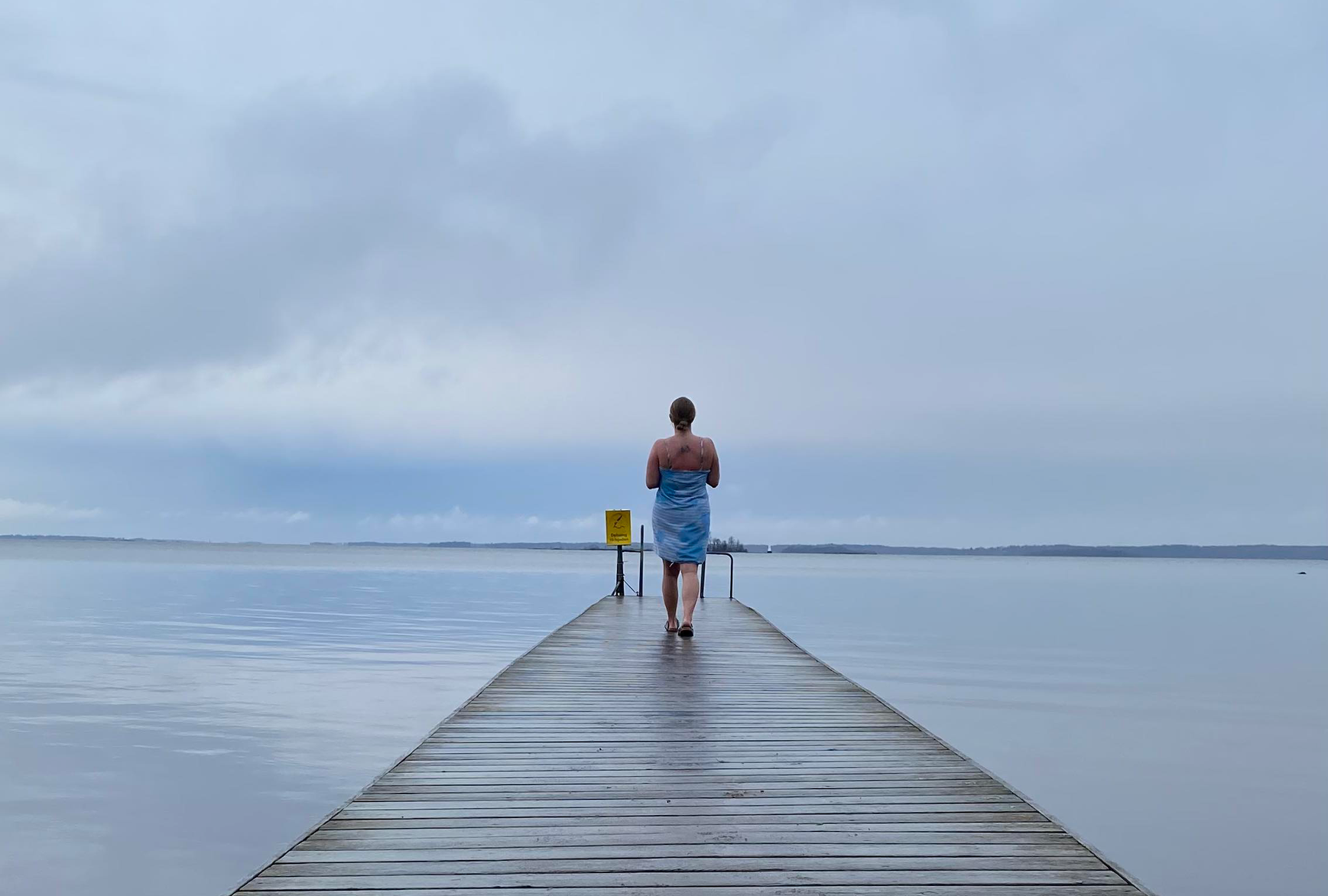 En person går på en brygga på en handduk virad om kroppen.